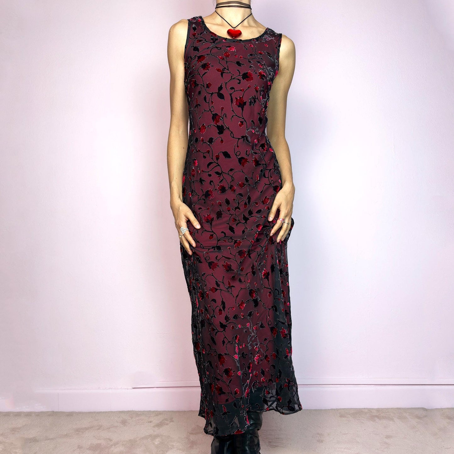 The Vintage 90s Black Sheer Floral Midi Dress is a striking piece featuring a sheer black overlay with textured velvet floral details layered over a vibrant red lining. The sleeveless design and round neckline offer a timeless silhouette, while the fitted shape and midi length create a flattering, romantic look. The fabric is slightly stretchy and flowy, with a gothic romantic vibe perfect for dark fairycore, witchy looks, or 2000s party aesthetics. Excellent vintage condition.
