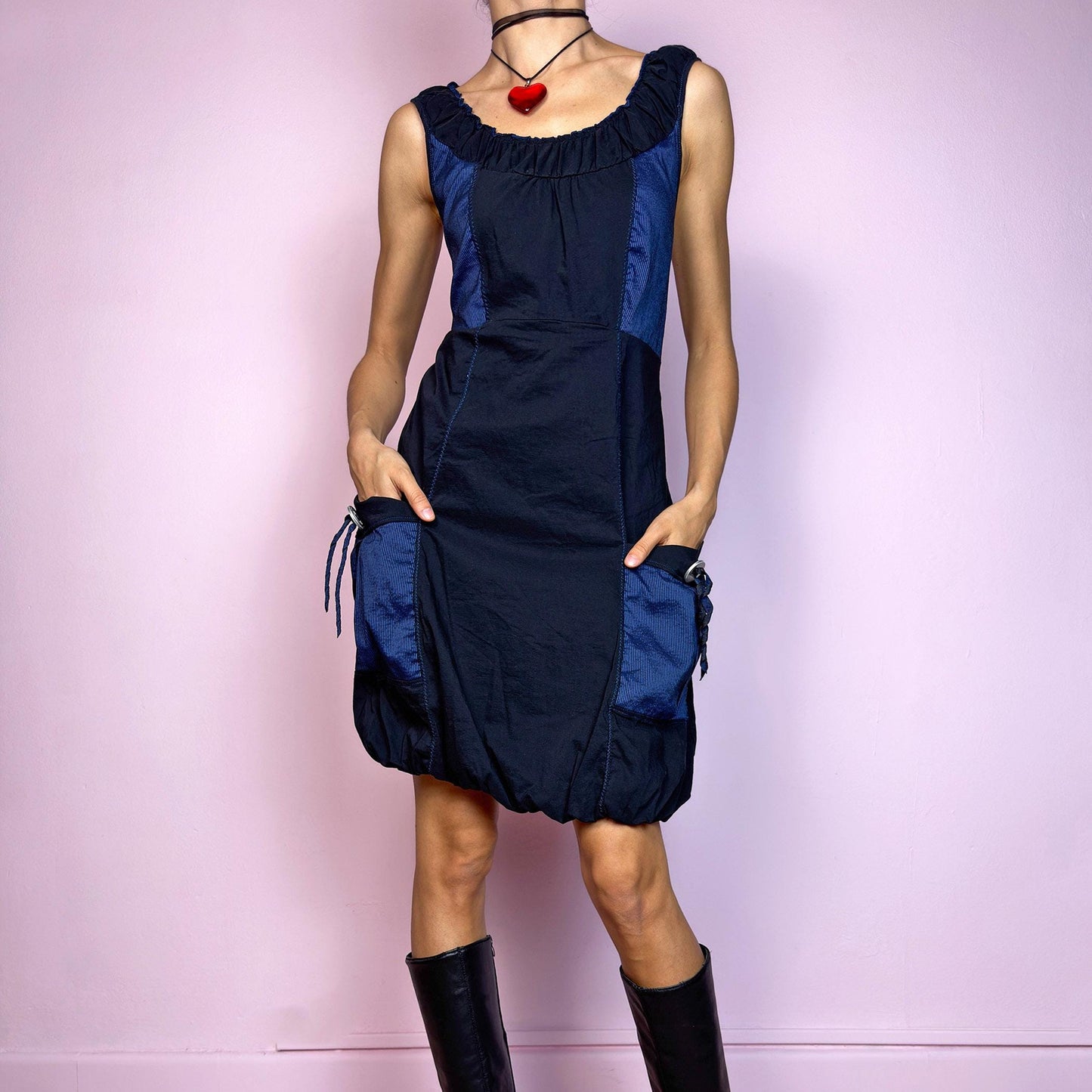 The Y2K Navy & Black Bubble Mini Dress is a bold vintage 2000s statement piece with utility-inspired vibes. Features a unique bubble hem, ruched scoop neckline, and structured paneled design with contrast navy inserts. Equipped with chunky side pockets and metal ring details for an industrial touch. Made from a stretchy fabric with a techy texture. Perfect for dystopian streetwear, cyber grunge, or Harajuku styling. Great vintage condition.
