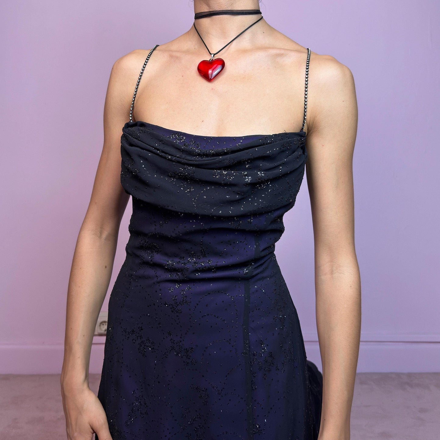 Step into the night in this breathtaking vintage 90s formal black glitter maxi dress. Crafted from a deep purple base with a sheer black overlay, it features all-over subtle glitter details that catch the light with every move. The draped cowl neckline adds soft elegance, while the delicate spaghetti straps are adorned with shimmering rhinestones for that extra sparkle. Designed with a flattering fit and a back zipper closure for ease and shape. A rare celestial piece – ideal for prom.
