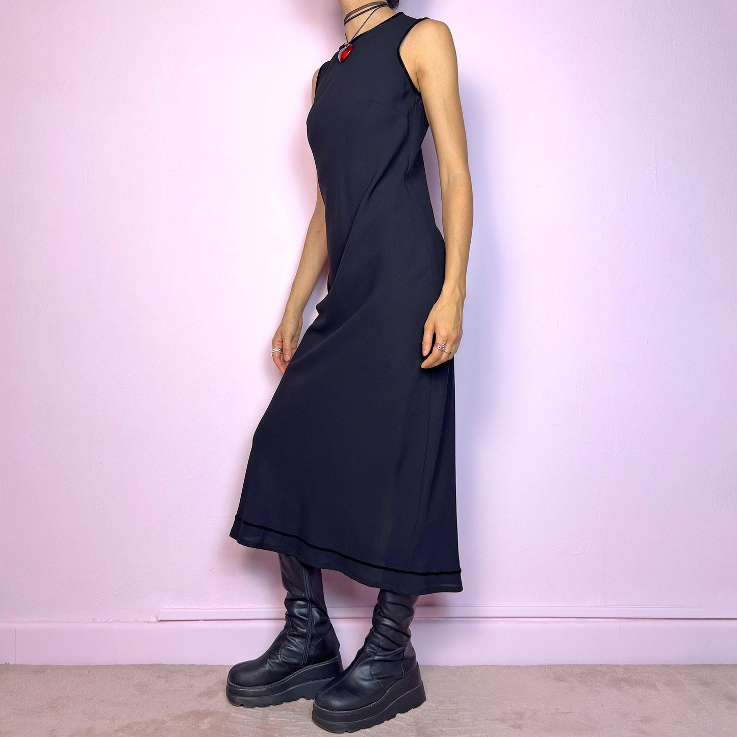 The Y2K Minimalist Black Midi Dress is a vintage 2000s sleek and timeless piece featuring a sleeveless design, and a slim, flattering fit. Crafted with lightweight, slightly sheer fabric, it drapes beautifully along the body and ends in a classic midi length. Features a back zipper closure and a back slit for ease of movement and an elegant touch. Perfect for minimalist, officecore, or elegant 90s-inspired looks. Effortlessly versatile for both casual layering and dressier night-out outfits.