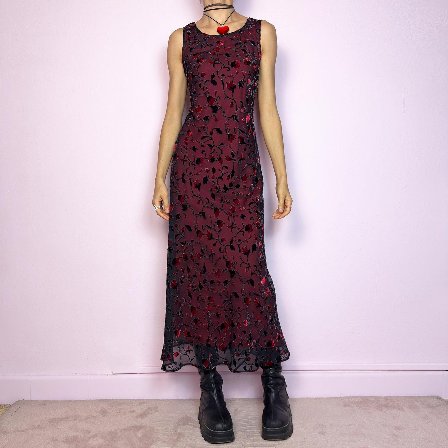 The Vintage 90s Black Sheer Floral Midi Dress is a striking piece featuring a sheer black overlay with textured velvet floral details layered over a vibrant red lining. The sleeveless design and round neckline offer a timeless silhouette, while the fitted shape and midi length create a flattering, romantic look. The fabric is slightly stretchy and flowy, with a gothic romantic vibe perfect for dark fairycore, witchy looks, or 2000s party aesthetics. Excellent vintage condition.