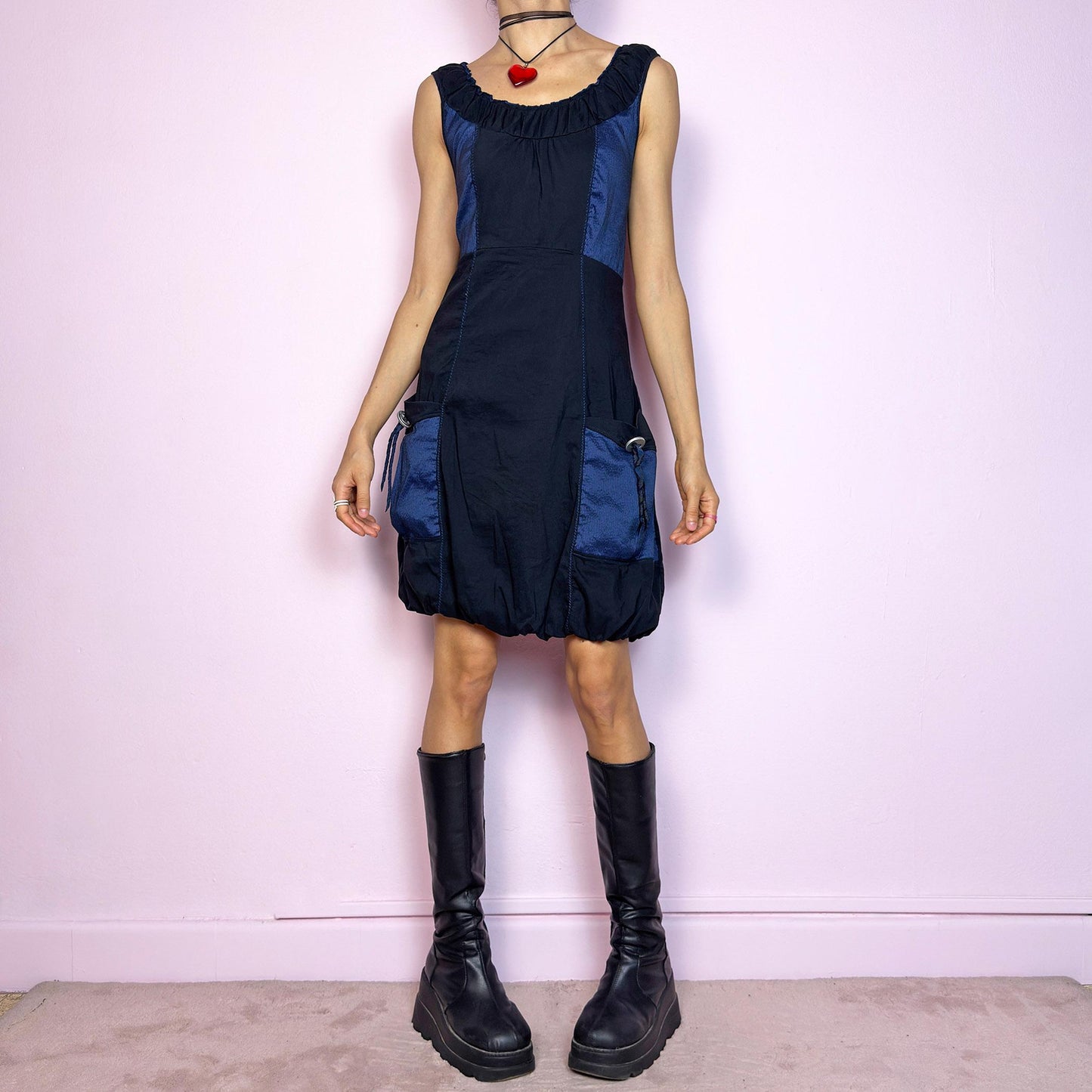 The Y2K Navy & Black Bubble Mini Dress is a bold vintage 2000s statement piece with utility-inspired vibes. Features a unique bubble hem, ruched scoop neckline, and structured paneled design with contrast navy inserts. Equipped with chunky side pockets and metal ring details for an industrial touch. Made from a stretchy fabric with a techy texture. Perfect for dystopian streetwear, cyber grunge, or Harajuku styling. Great vintage condition.
