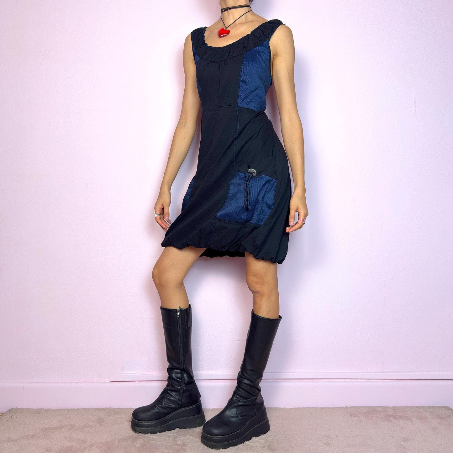 The Y2K Navy & Black Bubble Mini Dress is a bold vintage 2000s statement piece with utility-inspired vibes. Features a unique bubble hem, ruched scoop neckline, and structured paneled design with contrast navy inserts. Equipped with chunky side pockets and metal ring details for an industrial touch. Made from a stretchy fabric with a techy texture. Perfect for dystopian streetwear, cyber grunge, or Harajuku styling. Great vintage condition.