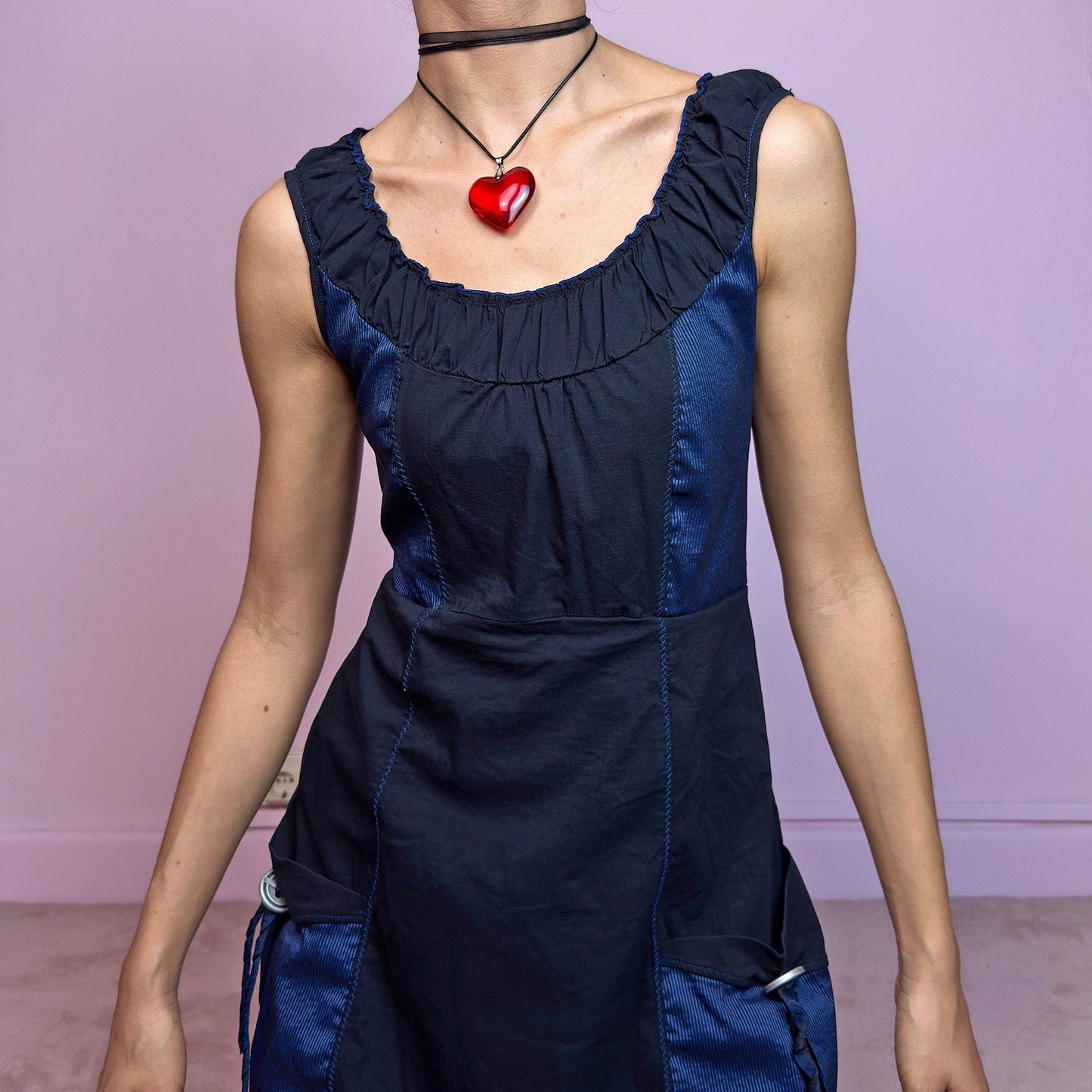 The Y2K Navy & Black Bubble Mini Dress is a bold vintage 2000s statement piece with utility-inspired vibes. Features a unique bubble hem, ruched scoop neckline, and structured paneled design with contrast navy inserts. Equipped with chunky side pockets and metal ring details for an industrial touch. Made from a stretchy fabric with a techy texture. Perfect for dystopian streetwear, cyber grunge, or Harajuku styling. Great vintage condition.
