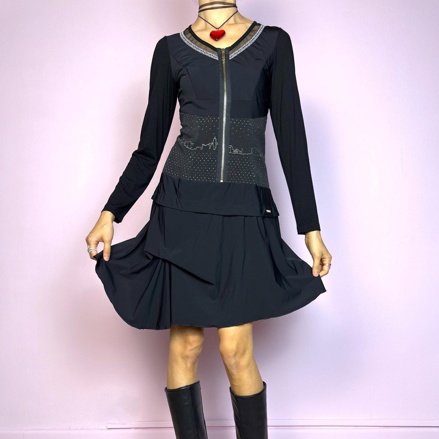 The Y2K Black Long Sleeve Mini Dress is a vintage 2000s sleek and deconstructed mini dress featuring a fitted bodice with a front zipper and a glittery cityscape detail at the waist. The long sleeves balance the edgy vibe of the layered, asymmetrical skirt, giving it a sculptural silhouette. Stretchy and comfortable, this dress is perfect for cybercore and futuristic clubwear. Great vintage condition.