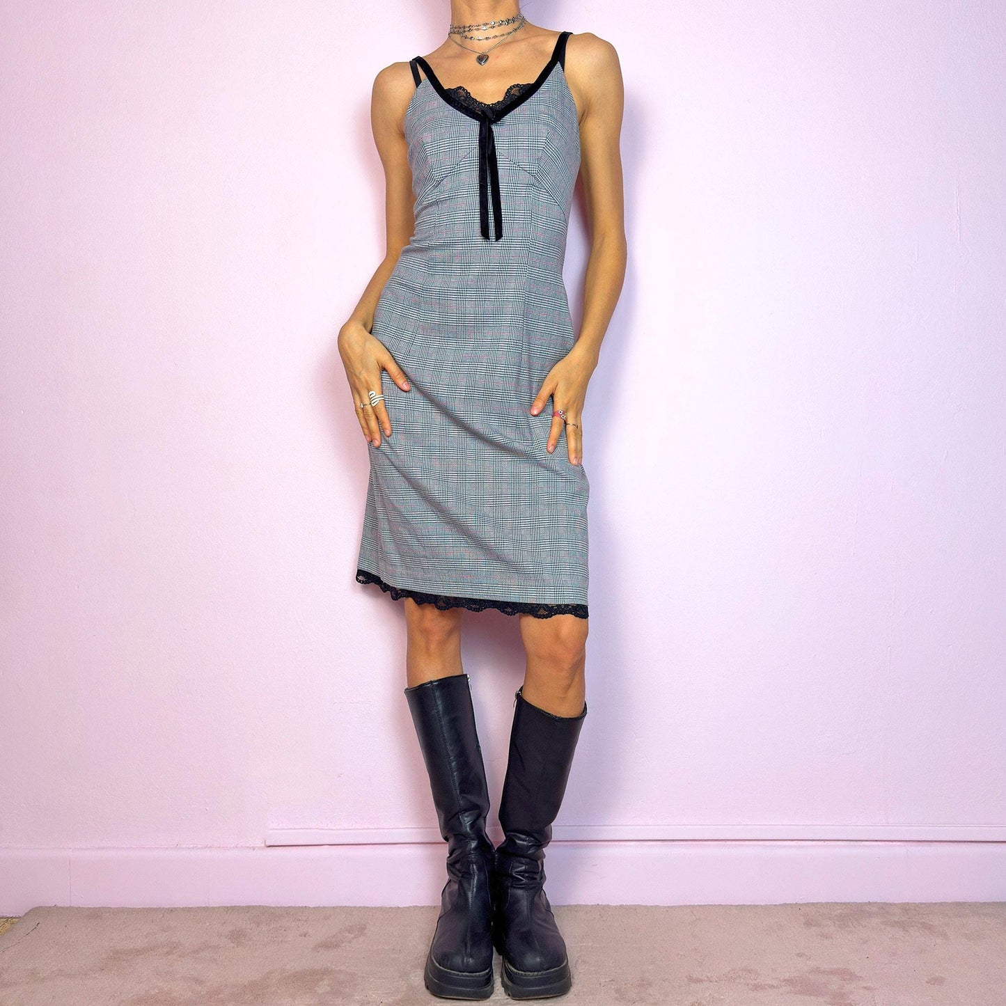 This vintage 2000s slip dress features a gray plaid print with black lace trim and a velvet bow at the bust. It has adjustable straps, a hidden back zipper, mid-length hem, and subtle stretch. The lingerie-inspired cut blends romantic and preppy codes, perfect for summer or layered transitions. A sleek office-core silhouette with soft edge—equal parts elegance and vintage 2000s attitude. Excellent vintage condition.