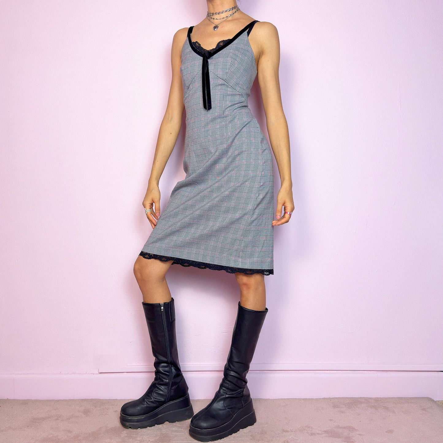 This vintage 2000s slip dress features a gray plaid print with black lace trim and a velvet bow at the bust. It has adjustable straps, a hidden back zipper, mid-length hem, and subtle stretch. The lingerie-inspired cut blends romantic and preppy codes, perfect for summer or layered transitions. A sleek office-core silhouette with soft edge—equal parts elegance and vintage 2000s attitude. Excellent vintage condition.