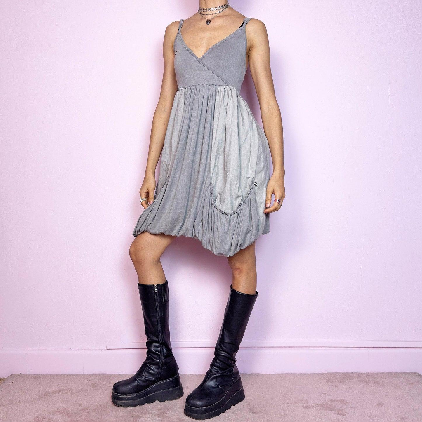 This vintage 2000s mini dress features a soft grey palette, deep wrap V-neckline, and empire waist with adjustable straps and light stretch. The voluminous bubble hem and oversized ruched pockets create sculptural movement and playful volume. Perfect for summer. A cyber-futuristic, deconstructed silhouette—airy, offbeat, and effortlessly cool. Excellent vintage condition.