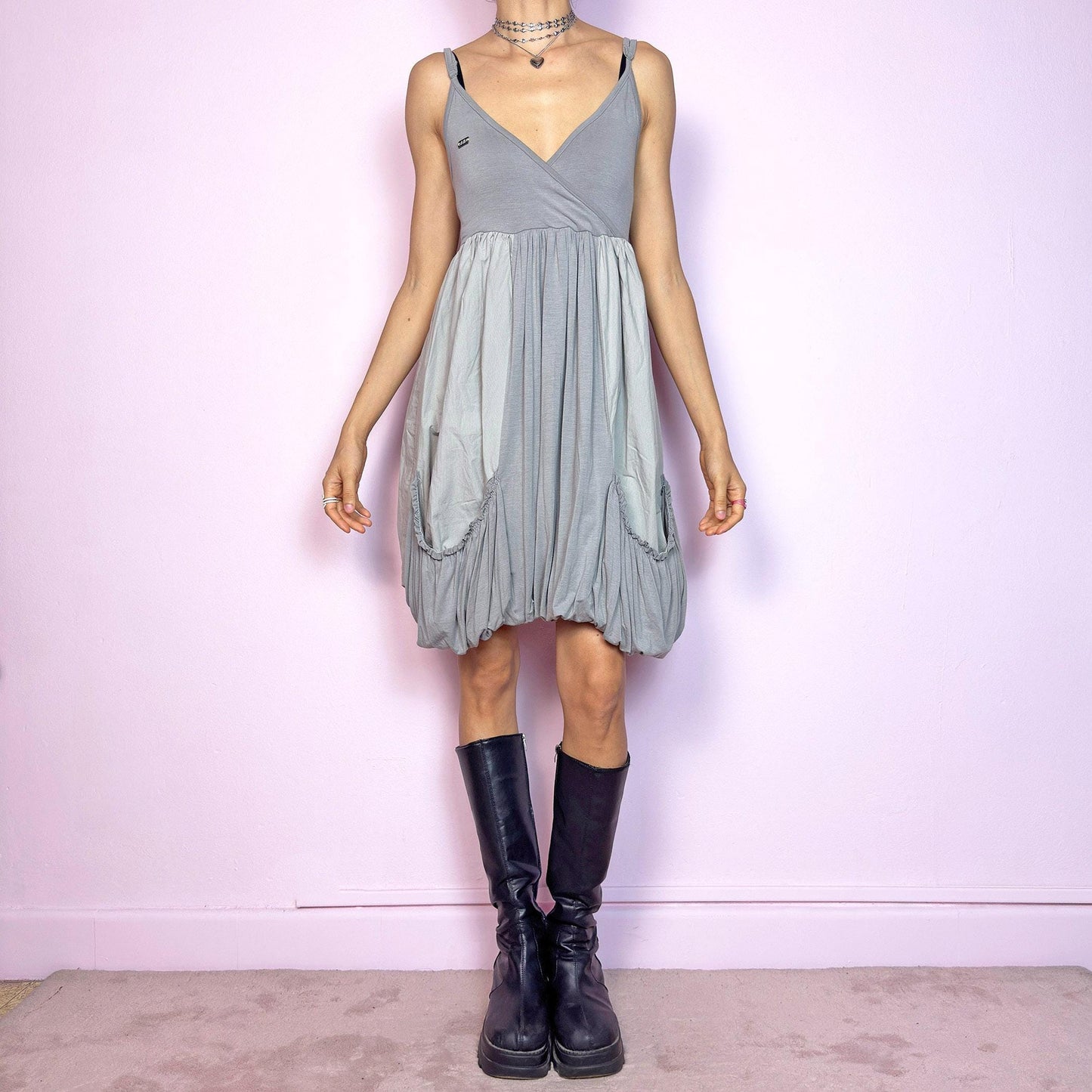 This vintage 2000s mini dress features a soft grey palette, deep wrap V-neckline, and empire waist with adjustable straps and light stretch. The voluminous bubble hem and oversized ruched pockets create sculptural movement and playful volume. Perfect for summer. A cyber-futuristic, deconstructed silhouette—airy, offbeat, and effortlessly cool. Excellent vintage condition.