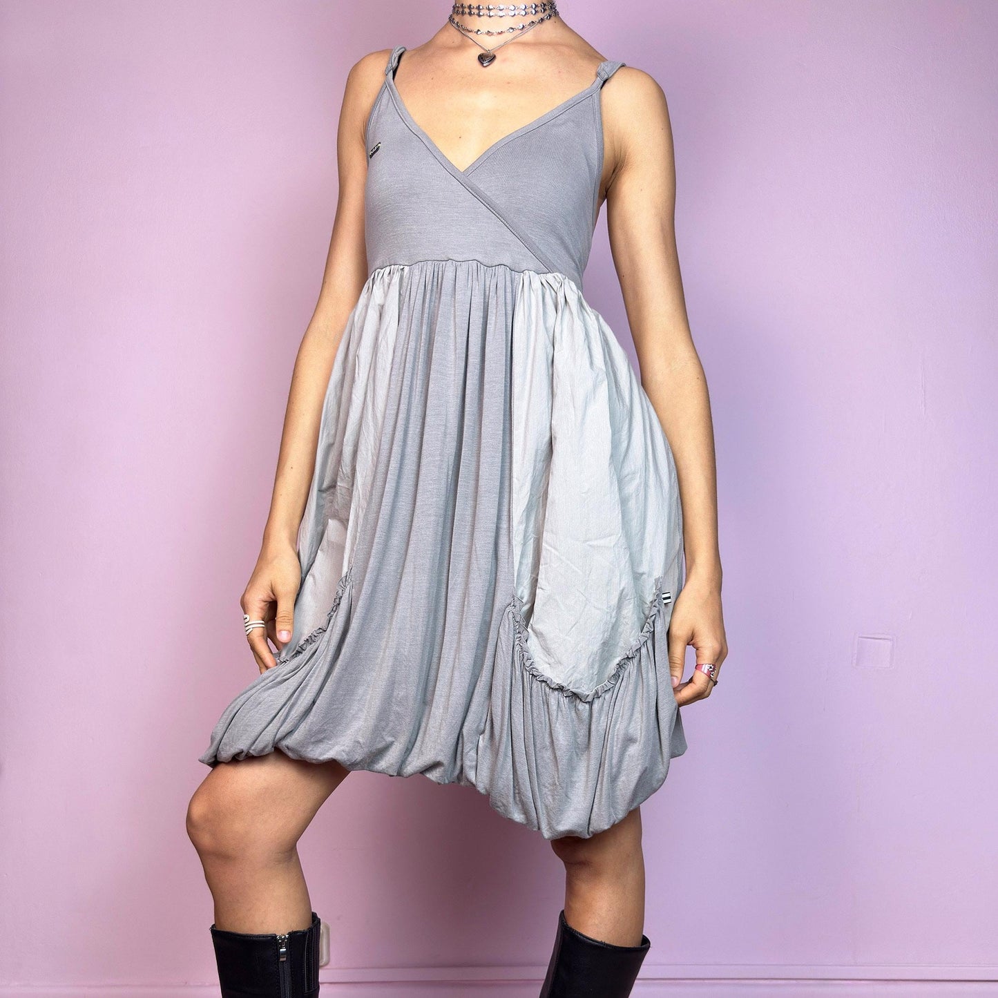 This vintage 2000s mini dress features a soft grey palette, deep wrap V-neckline, and empire waist with adjustable straps and light stretch. The voluminous bubble hem and oversized ruched pockets create sculptural movement and playful volume. Perfect for summer. A cyber-futuristic, deconstructed silhouette—airy, offbeat, and effortlessly cool. Excellent vintage condition.