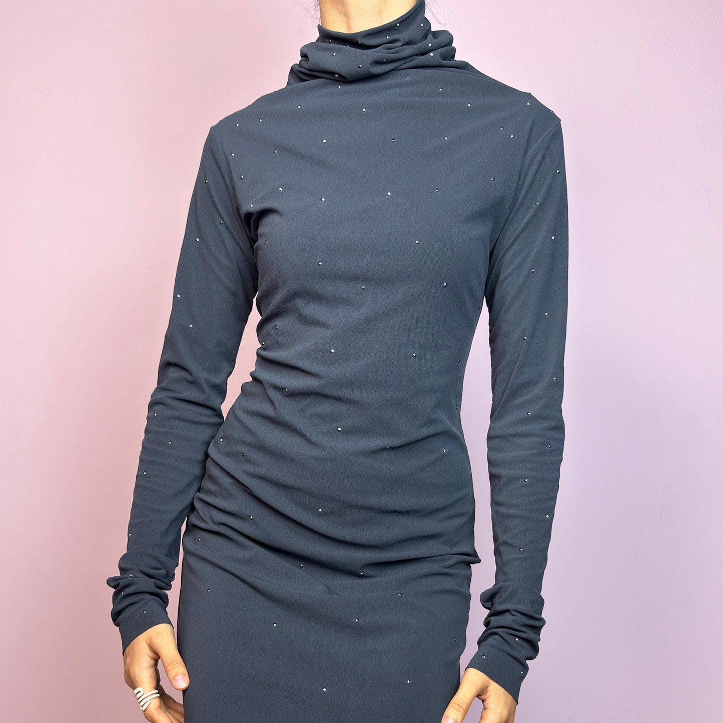 This vintage 2000s grey mini dress is cut from stretchy mesh jersey with an elegant turtleneck and long sleeves. Subtle rhinestones are scattered throughout, catching light with a soft shimmer. The bodycon silhouette hugs the figure with ease. No closure, easy pull-on style. A minimalist Y2K piece with glam undertones—perfect for winter nights, parties, or city outings. Made in Italy. Excellent vintage condition.