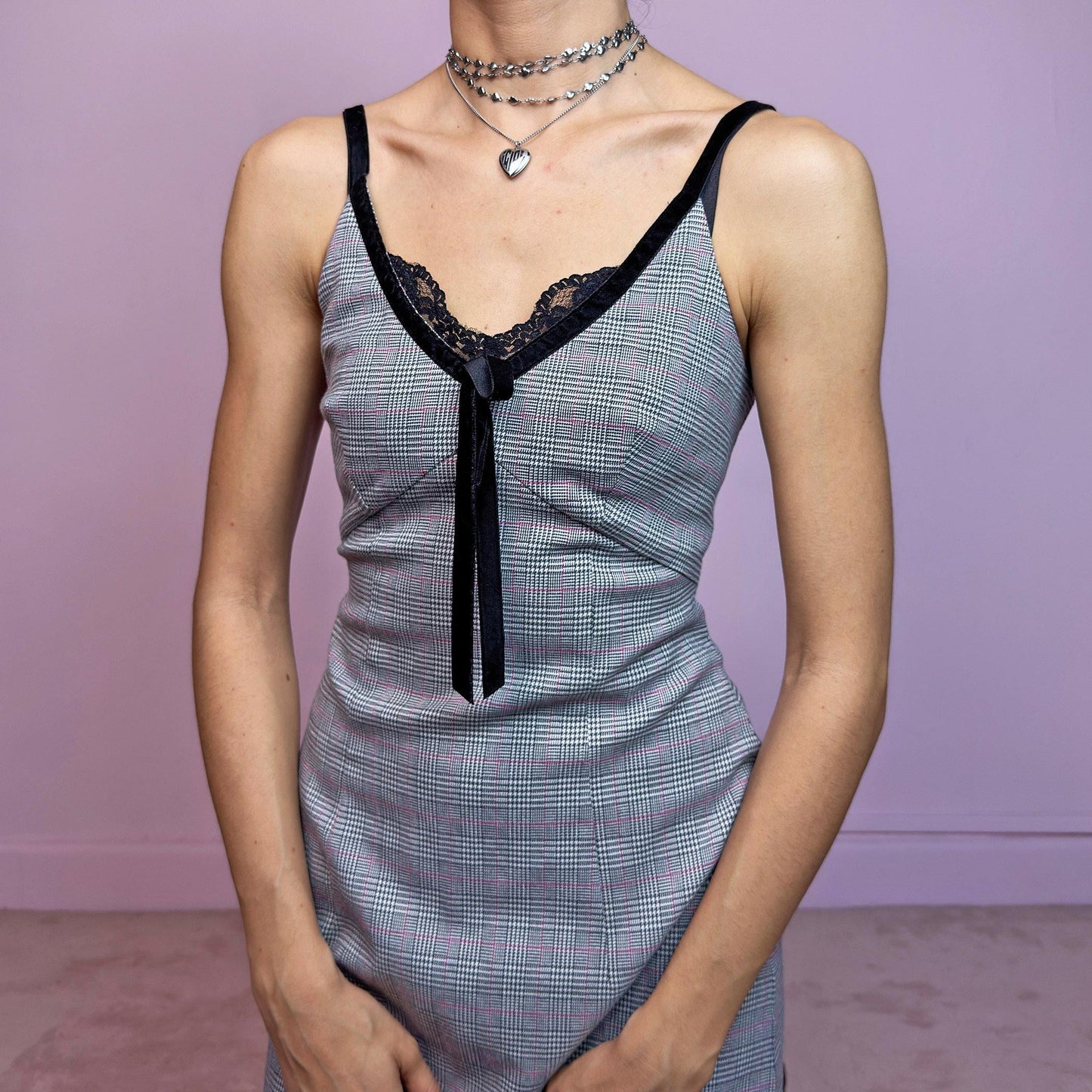 This vintage 2000s slip dress features a gray plaid print with black lace trim and a velvet bow at the bust. It has adjustable straps, a hidden back zipper, mid-length hem, and subtle stretch. The lingerie-inspired cut blends romantic and preppy codes, perfect for summer or layered transitions. A sleek office-core silhouette with soft edge—equal parts elegance and vintage 2000s attitude. Excellent vintage condition.