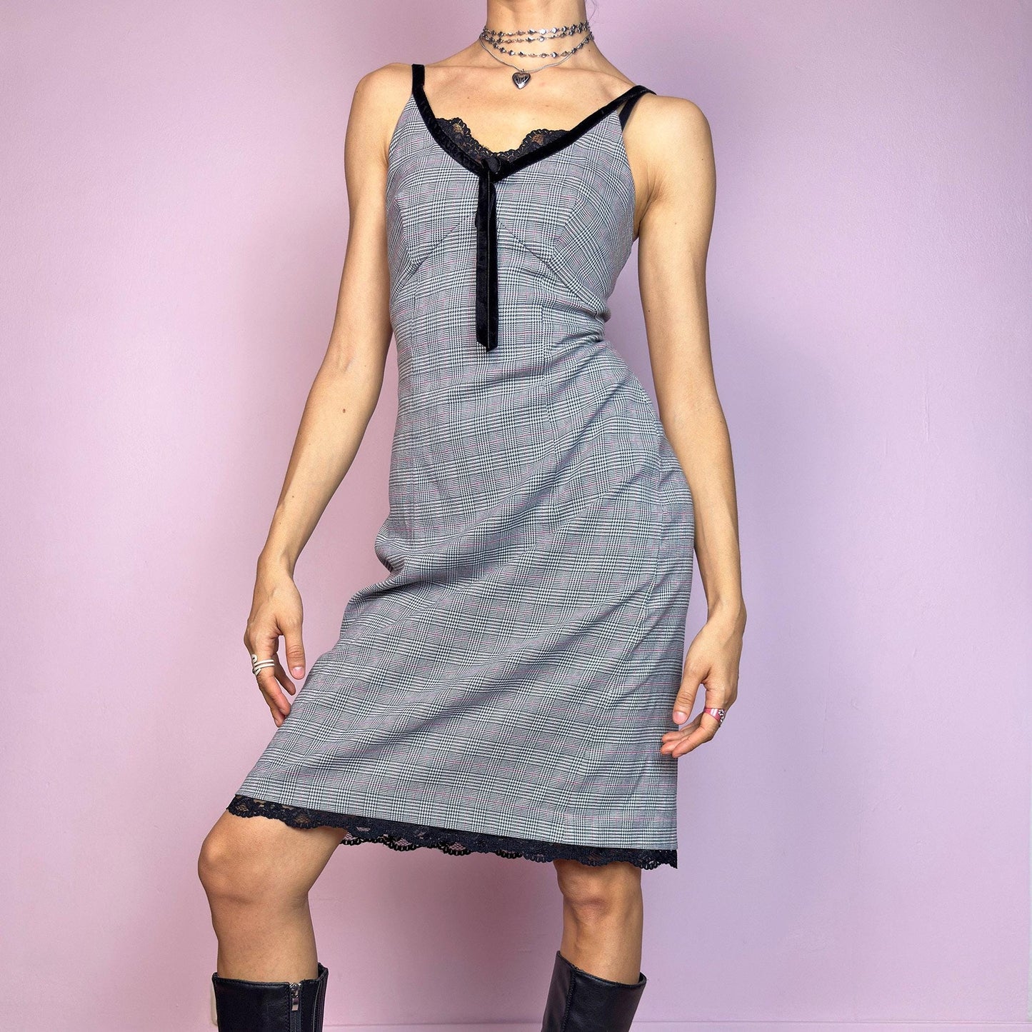 This vintage 2000s slip dress features a gray plaid print with black lace trim and a velvet bow at the bust. It has adjustable straps, a hidden back zipper, mid-length hem, and subtle stretch. The lingerie-inspired cut blends romantic and preppy codes, perfect for summer or layered transitions. A sleek office-core silhouette with soft edge—equal parts elegance and vintage 2000s attitude. Excellent vintage condition.