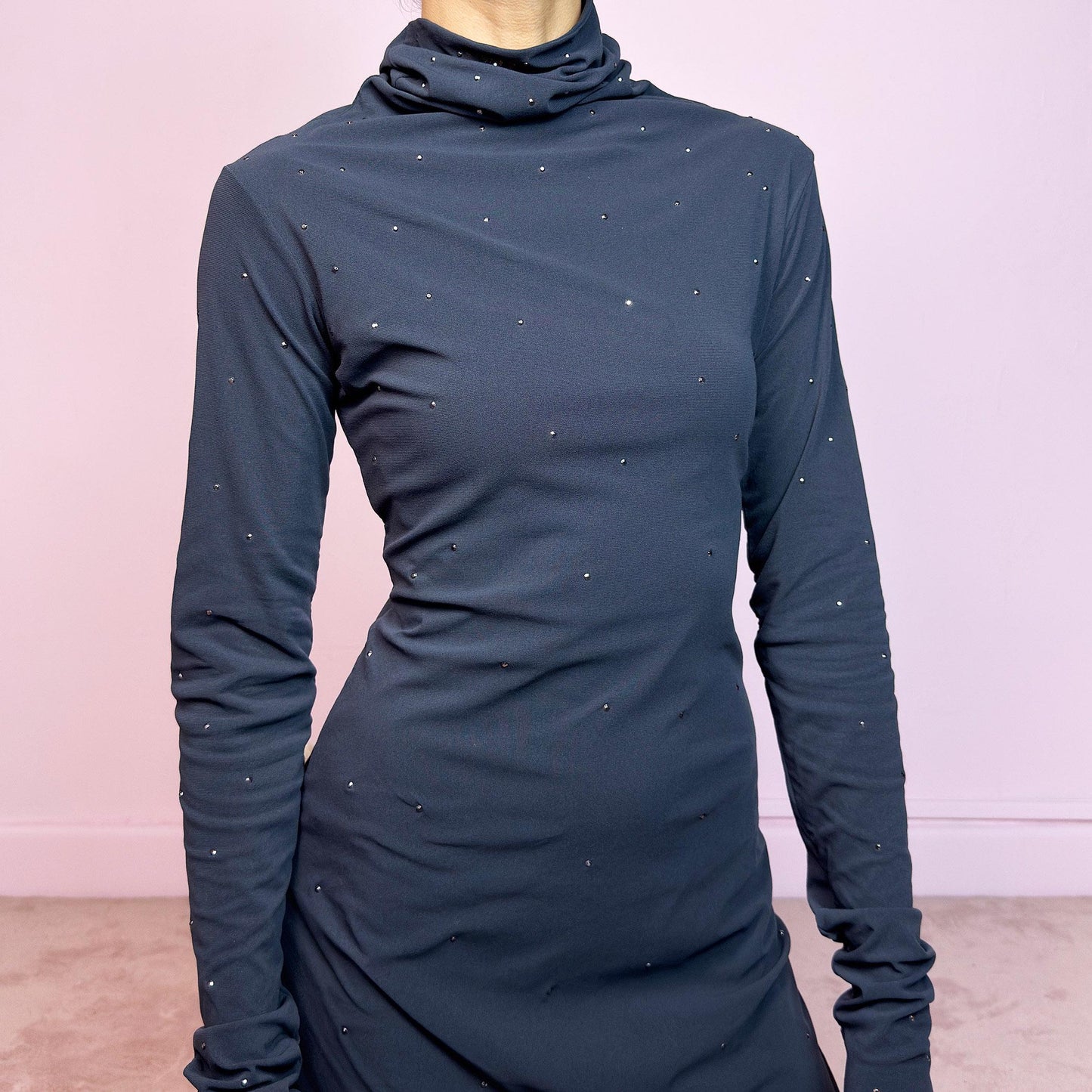 This vintage 2000s grey mini dress is cut from stretchy mesh jersey with an elegant turtleneck and long sleeves. Subtle rhinestones are scattered throughout, catching light with a soft shimmer. The bodycon silhouette hugs the figure with ease. No closure, easy pull-on style. A minimalist Y2K piece with glam undertones—perfect for winter nights, parties, or city outings. Made in Italy. Excellent vintage condition.