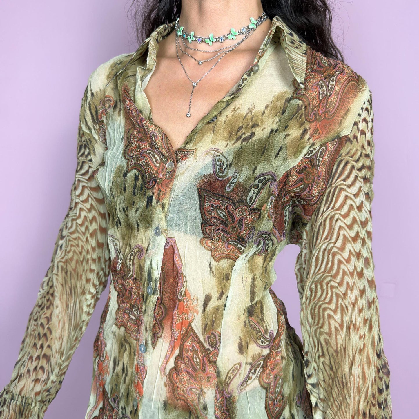 This vintage 2000s pleated sheer blouse blends soft sage green with wild paisley and animal-inspired prints in rust and brown. Features include tie details at the flared cuffs and a sharp pointed collar. A lightweight, breathable layer ideal for transitional styling, evening events, or a creative summer escapade in the Mediterranean. A rare, print-rich piece channeling bohemian and surrealist textures. Excellent vintage condition.