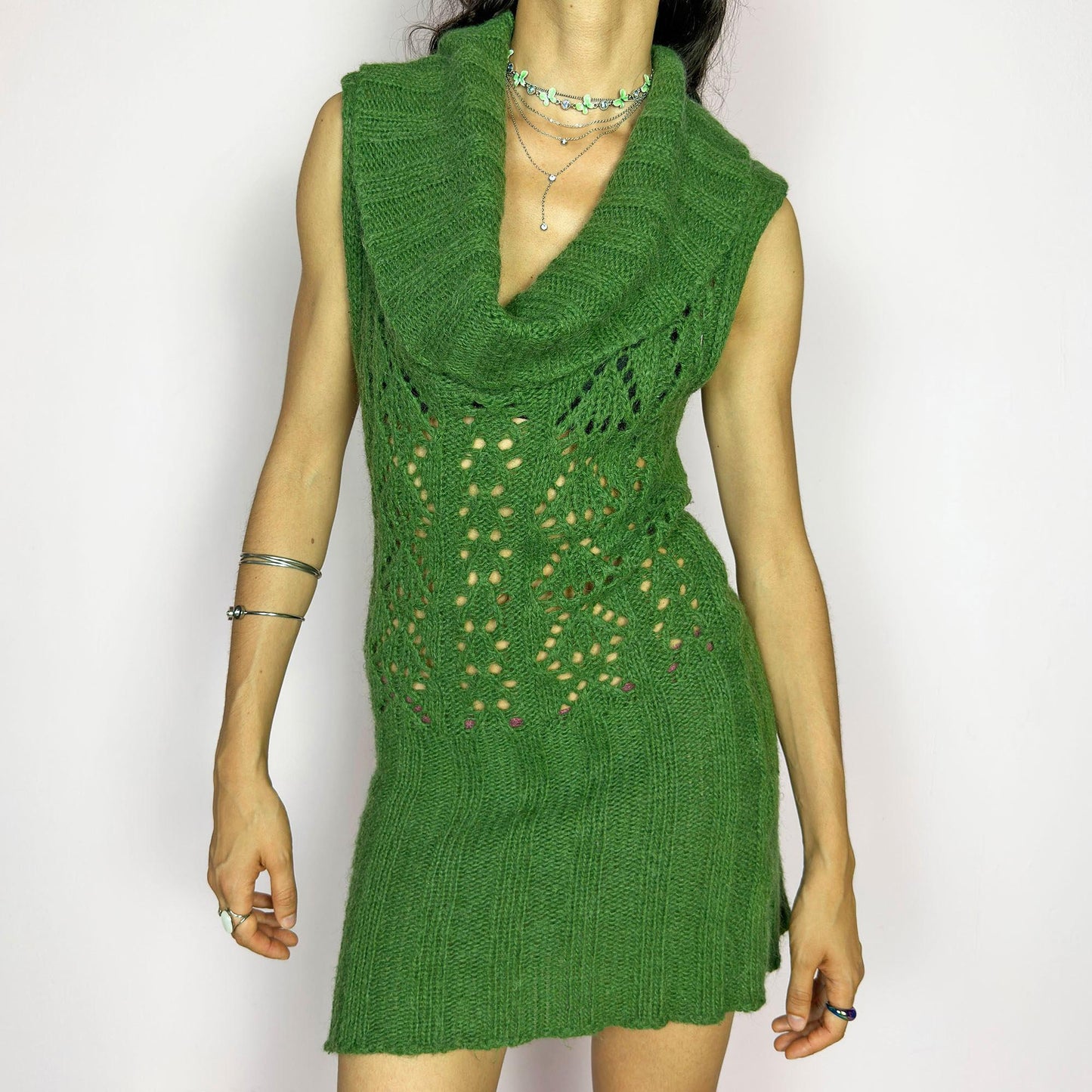 This vintage 2000s green knit mini dress features a dramatic cowl neckline, sleeveless cut, and decorative open knit pattern through the torso. Softly fitted and slightly sheer—perfect for lounging by the fire on a rustic weekend escape. A super comfy Y2K piece made in Spain. Made from an acrylic, polyamide, and mohair blend for soft warmth. Great vintage condition.