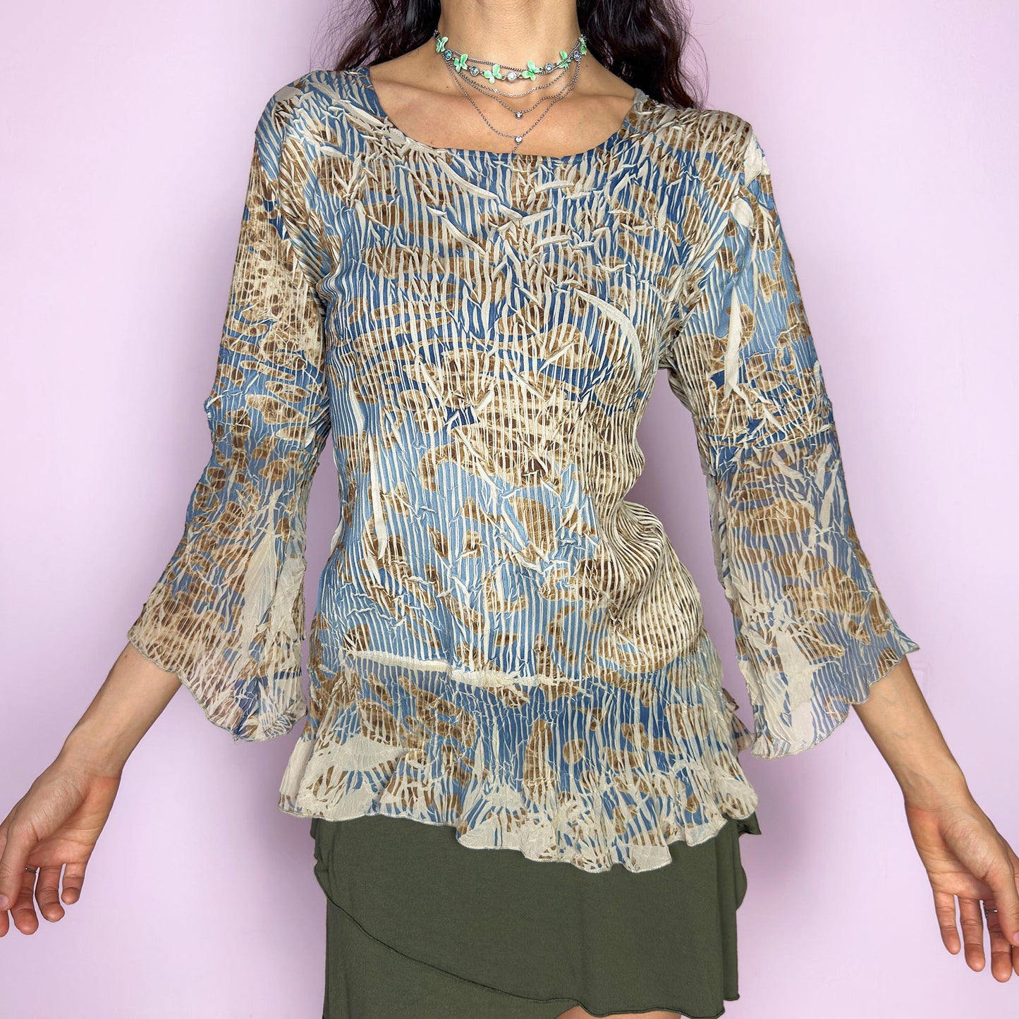 The vintage 2000s bell sleeve top is made in France with a crinkled textured finish. It features an abstract print in soft beige, slate blue, and brown, with a scoop neckline, three-quarter flared sleeves, and a ruffled hem. This blouse blends romantic texture with airy movement—an effortlessly elegant piece for formal avant garde events or earthy, whimsical styling. Made of polyester-spandex blend. Excellent vintage condition.