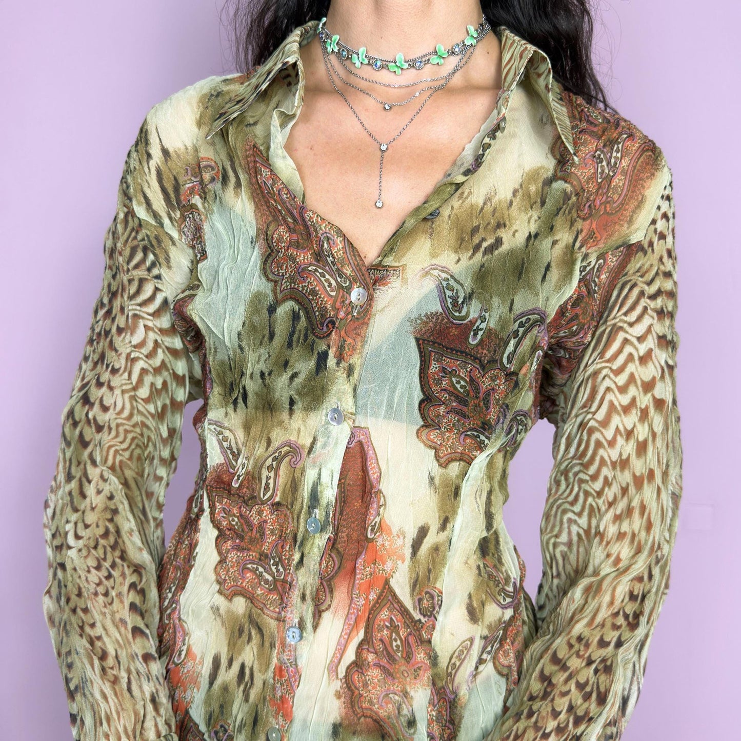 This vintage 2000s pleated sheer blouse blends soft sage green with wild paisley and animal-inspired prints in rust and brown. Features include tie details at the flared cuffs and a sharp pointed collar. A lightweight, breathable layer ideal for transitional styling, evening events, or a creative summer escapade in the Mediterranean. A rare, print-rich piece channeling bohemian and surrealist textures. Excellent vintage condition.