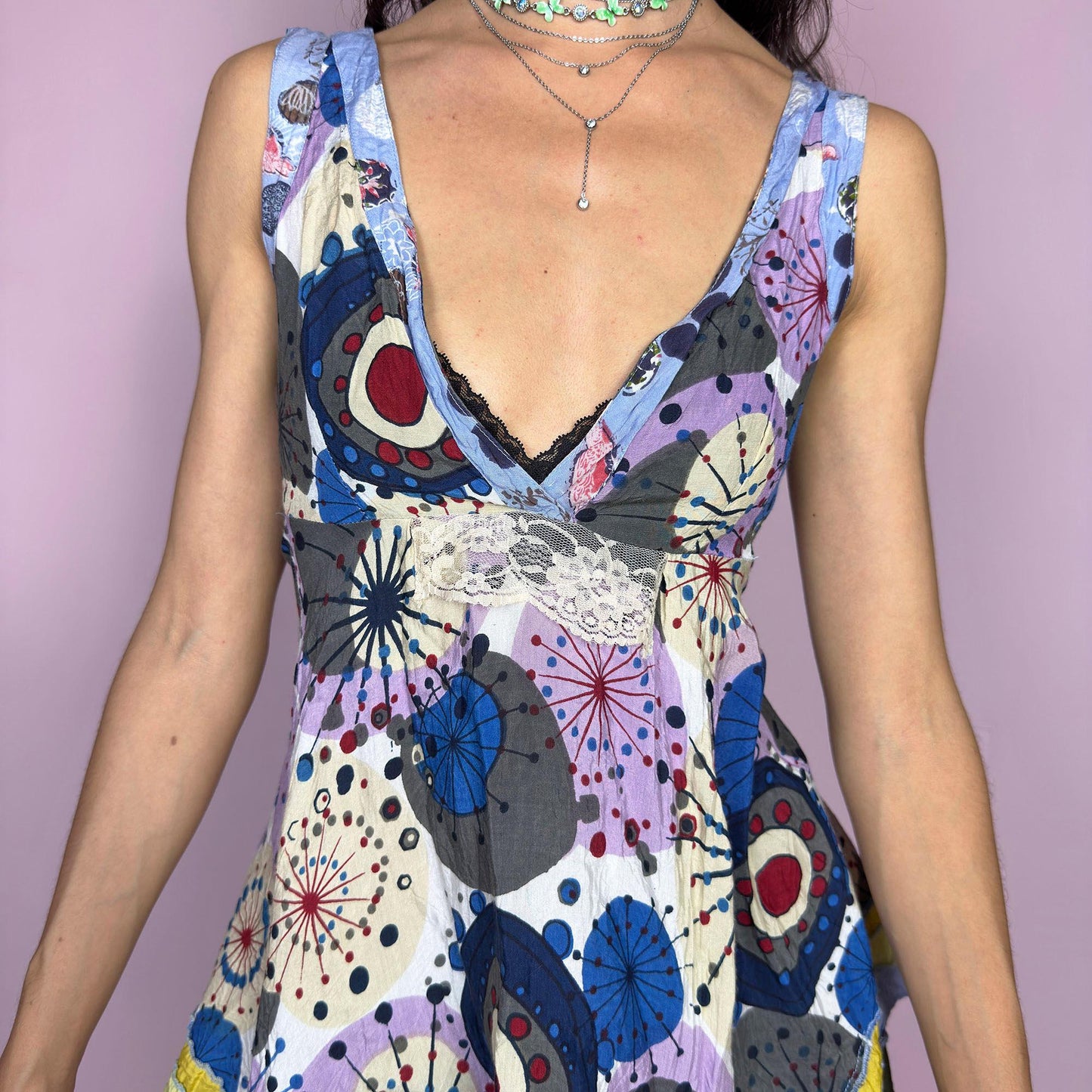This vintage 2000s tie-back top swirls with boho whimsy in a patchwork of abstract prints, soft purples, blues, and pops of yellow. The asymmetric hem, deep V neckline, and raw edge details channel ragged doll charm with gypsy spirit. Perfect for barefoot dancing, open-air festivals, or sun-drenched summer days. A flowy Y2K piece with playful movement and soul, from Desigual. Great vintage condition.