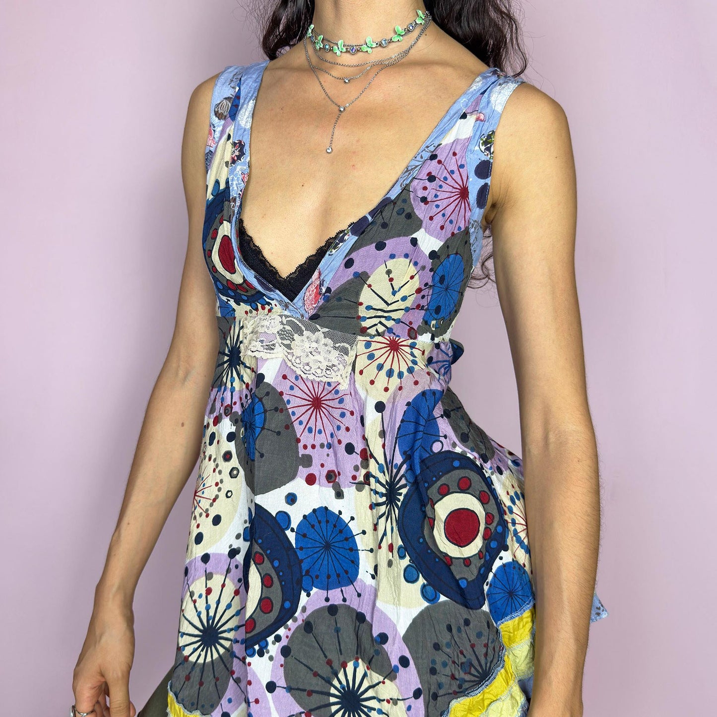 This vintage 2000s tie-back top swirls with boho whimsy in a patchwork of abstract prints, soft purples, blues, and pops of yellow. The asymmetric hem, deep V neckline, and raw edge details channel ragged doll charm with gypsy spirit. Perfect for barefoot dancing, open-air festivals, or sun-drenched summer days. A flowy Y2K piece with playful movement and soul, from Desigual. Great vintage condition.