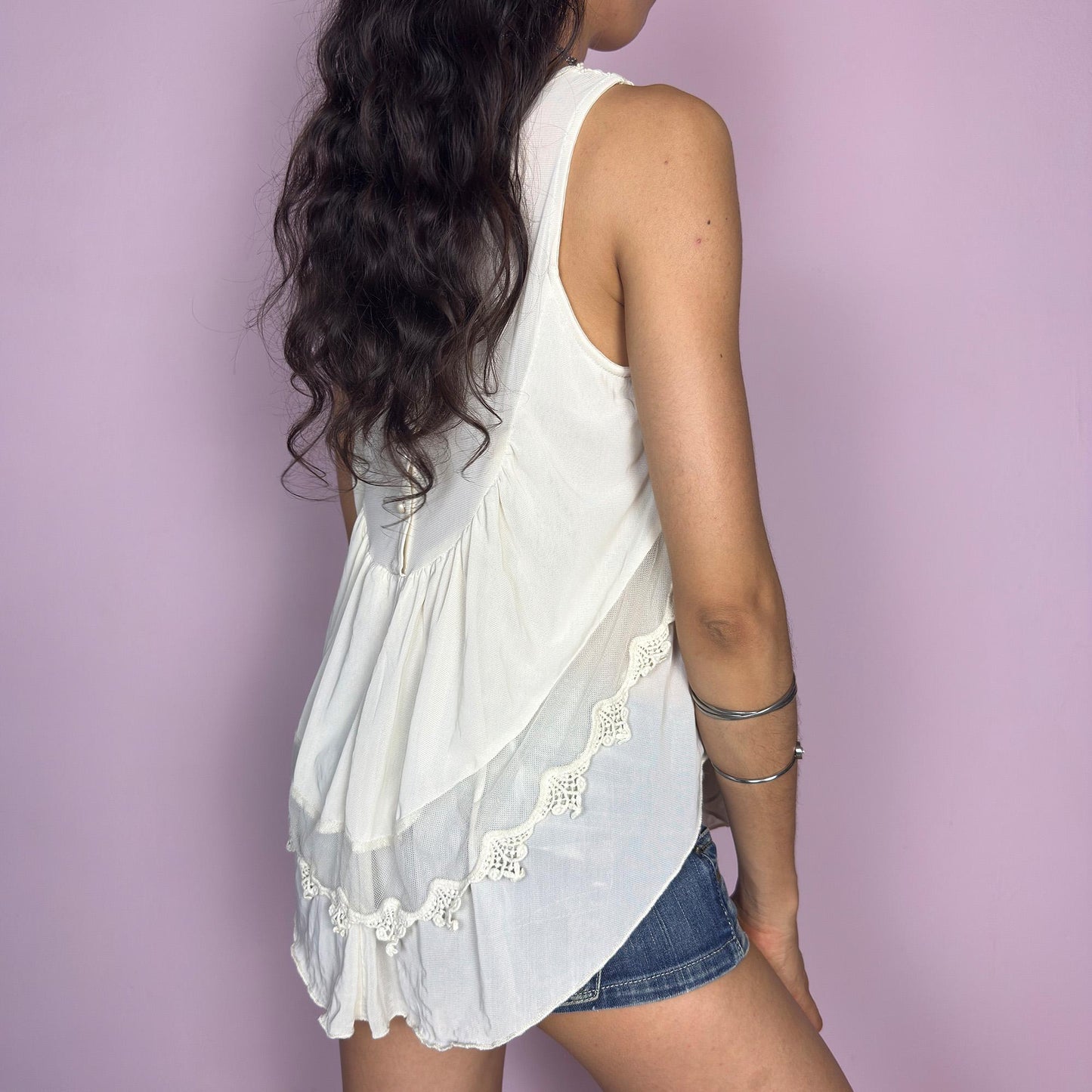 The Y2K Cream Lace Mesh Top is a vintage 2000s sleeveless blouse featuring intricate lace panels, soft layered mesh, and scalloped crochet trim. Designed with a relaxed fit and and a back button closure, this dreamy cream-toned piece evokes boho ease and festival charm. Lightweight and breathable, ideal for summer beach days, barefoot dancing, or ethereal layered styling. A soft silhouette with poetic movement. Excellent vintage condition.