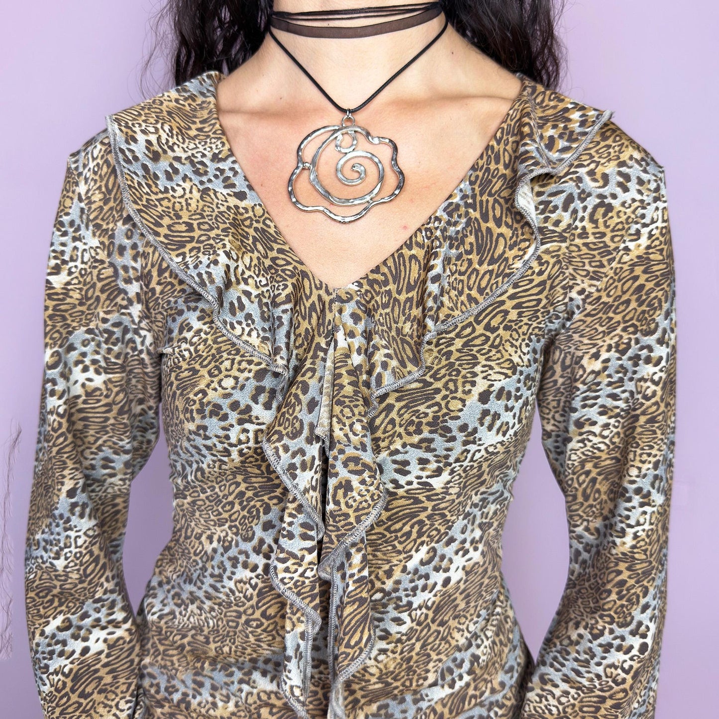 The Y2K Leopard Print Ruffle Top is a vintage 2000s blouse crafted from stretchy fabric with a bold allover animal print. It features a plunging V-neckline framed by cascading ruffles, three-quarter flared sleeves, and a flattering fit. Perfect for a glam kitschy 60s revival mood. Ideal for night-outs, themed parties, or standout casual looks. Great vintage condition.