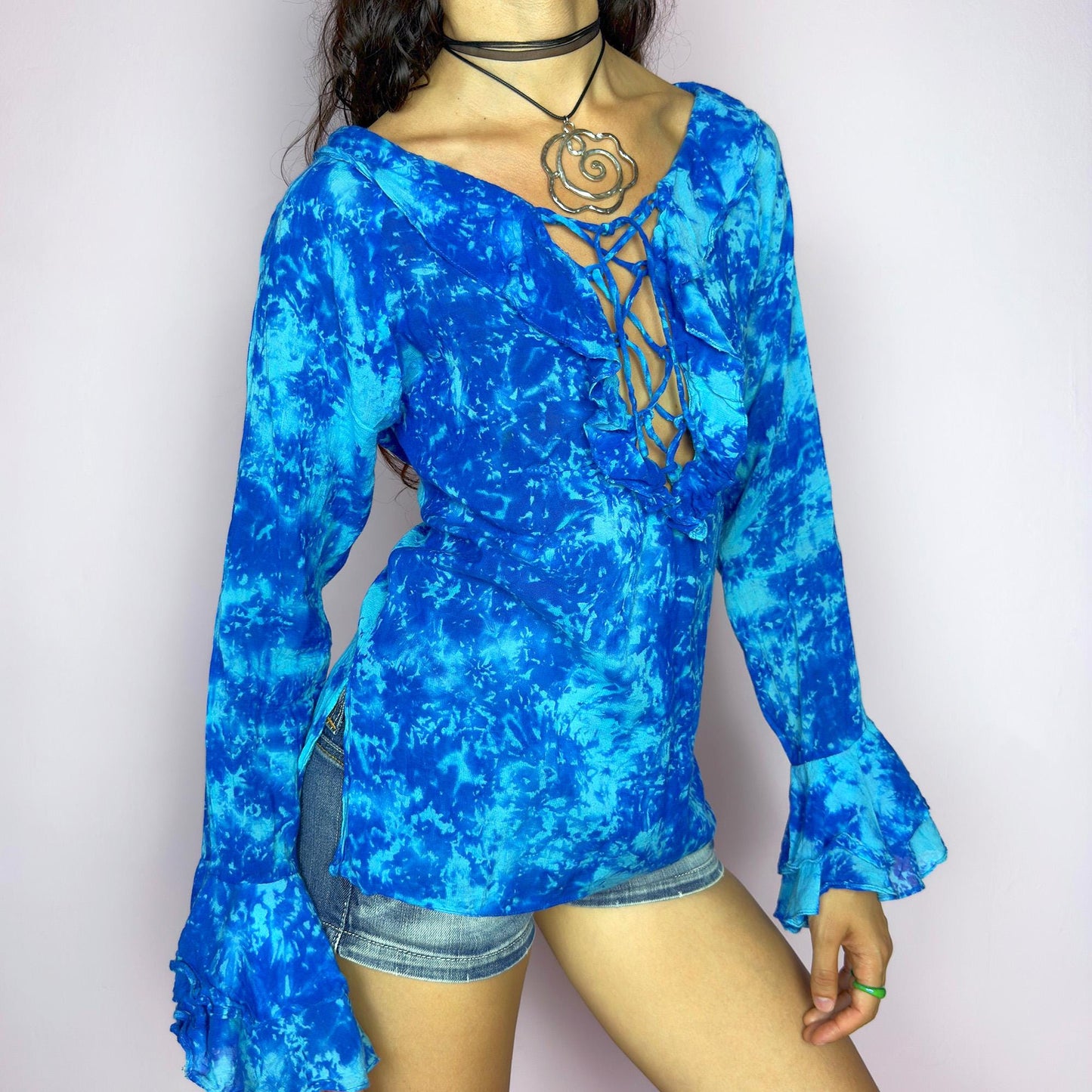 This vintage 90s blue tie dye top features dramatic ruffle cuffs, a deep lace-up neckline, and soft cotton-blend fabric in vibrant psychedelic tones. Designed with long sleeves it channels boho, hippie, and festival energy with bold originality. Lightweight and breathable, perfect for summer layering or statement styling. A rare archival blouse that captures wild 90s freedom. Excellent vintage condition.