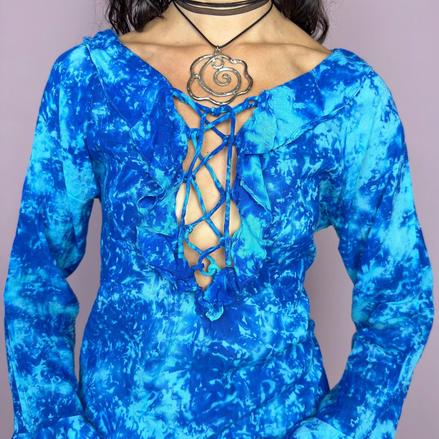 This vintage 90s blue tie dye top features dramatic ruffle cuffs, a deep lace-up neckline, and soft cotton-blend fabric in vibrant psychedelic tones. Designed with long sleeves it channels boho, hippie, and festival energy with bold originality. Lightweight and breathable, perfect for summer layering or statement styling. A rare archival blouse that captures wild 90s freedom. Excellent vintage condition.