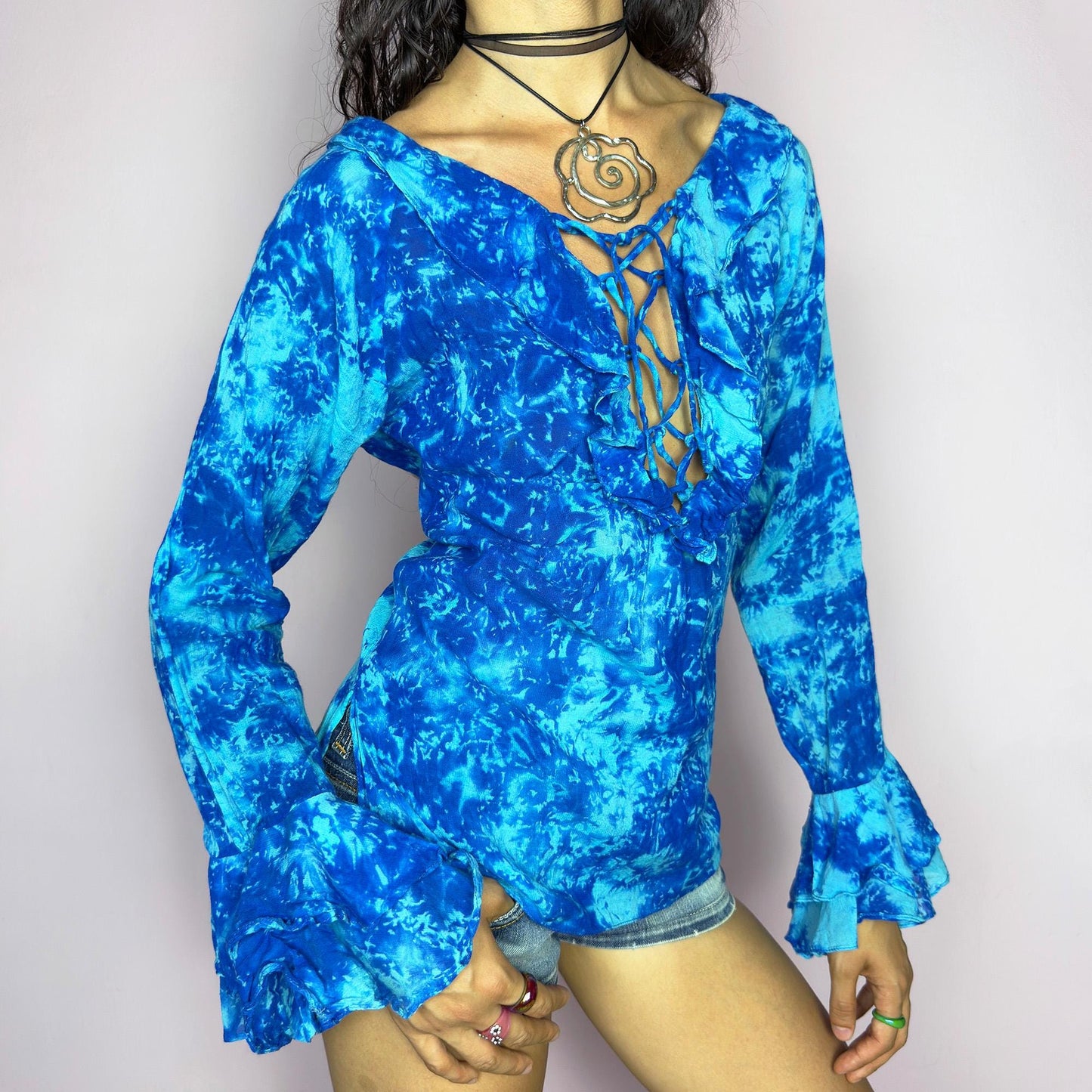 This vintage 90s blue tie dye top features dramatic ruffle cuffs, a deep lace-up neckline, and soft cotton-blend fabric in vibrant psychedelic tones. Designed with long sleeves it channels boho, hippie, and festival energy with bold originality. Lightweight and breathable, perfect for summer layering or statement styling. A rare archival blouse that captures wild 90s freedom. Excellent vintage condition.