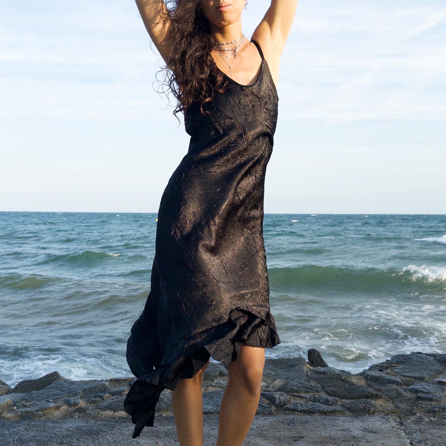 The vintage 2000s black slip dress is a made-in-France piece with crinkled texture and asymmetric ruffle hem. Its sculptural midi silhouette moves with quiet sensuality—ideal for gallery openings, formal nights, or late summer dates. A deconstructed Y2K shape that evokes avant-garde elegance, made to be seen without shouting. An archival dress crafted from a soft polyester blend. Excellent vintage condition.
