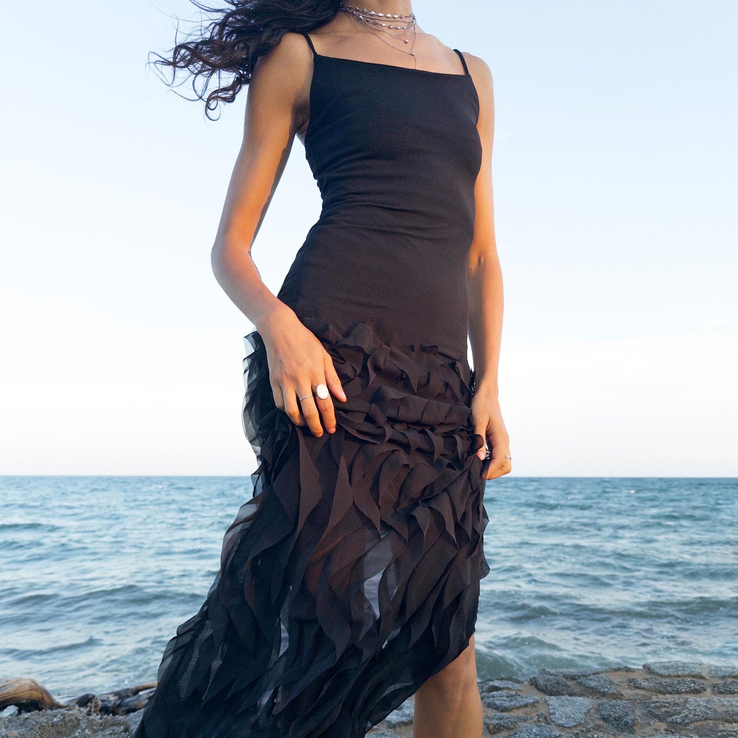 The vintage 90s black mesh midi dress is a sculptural piece with sheer wave appliqué layered across the skirt, minimalist neckline, and a back slit for fluidity. Its body-skimming silhouette fuses quiet sensuality with architectural edge. Ideal for city nights, gallery parties, or modern cocktail looks. An avant garde archive find made in the USA from a stretchy polyester blend. Excellent vintage condition.