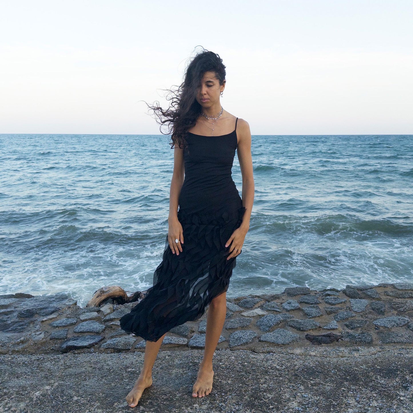The vintage 90s black mesh midi dress is a sculptural piece with sheer wave appliqué layered across the skirt, minimalist neckline, and a back slit for fluidity. Its body-skimming silhouette fuses quiet sensuality with architectural edge. Ideal for city nights, gallery parties, or modern cocktail looks. An avant garde archive find made in the USA from a stretchy polyester blend. Excellent vintage condition.