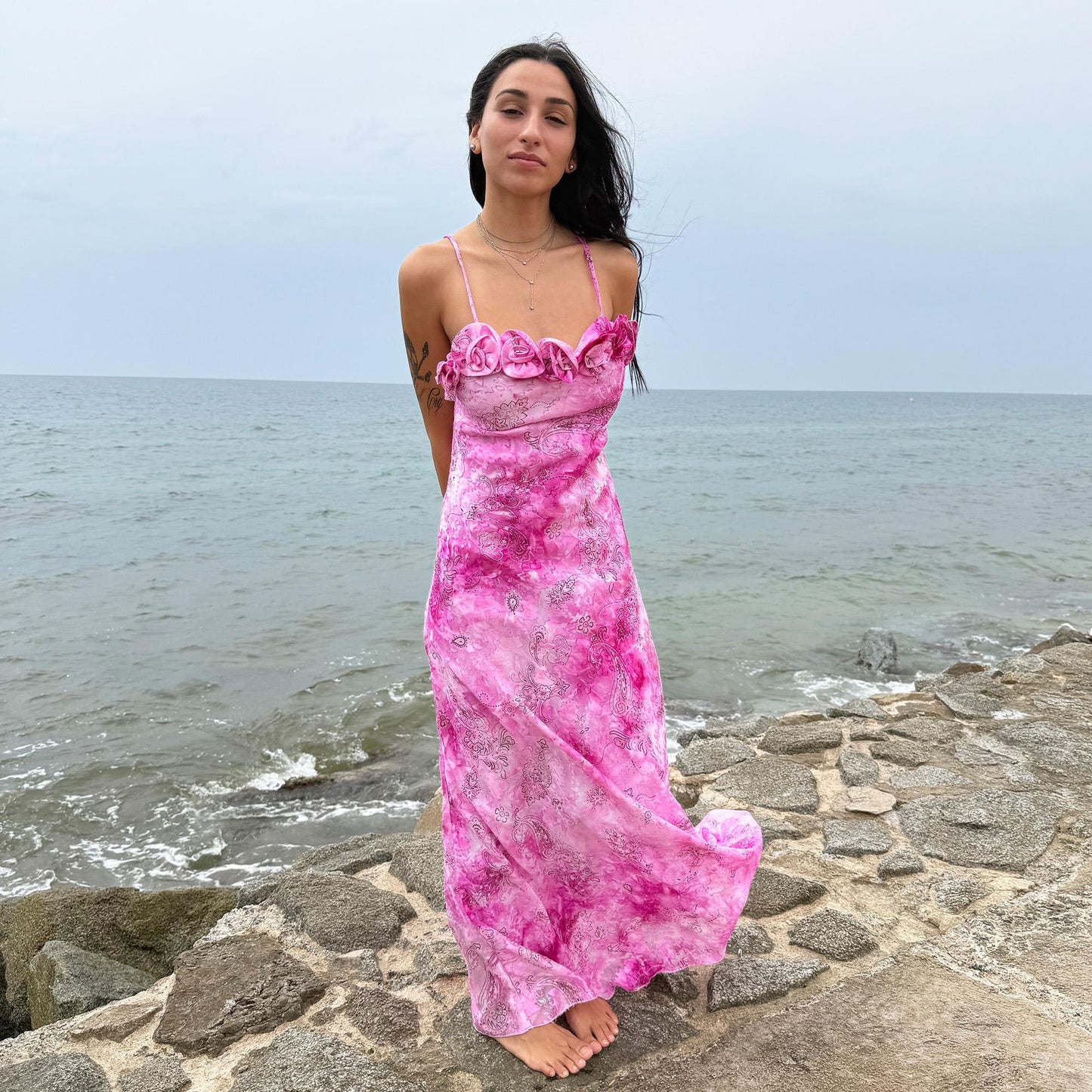 This vintage 2000s slip dress features a vivid pink tie-dye paisley print with rosette appliqué detail at the neckline. It flows into a long silhouette, ideal for summer weddings, proms, or formal parties, and comes with a matching scarf for versatile styling. A romantic archival piece made in France, perfect for bridal, evening, or statement occasions. Made from a non-stretch polyester blend. Excellent vintage condition.
