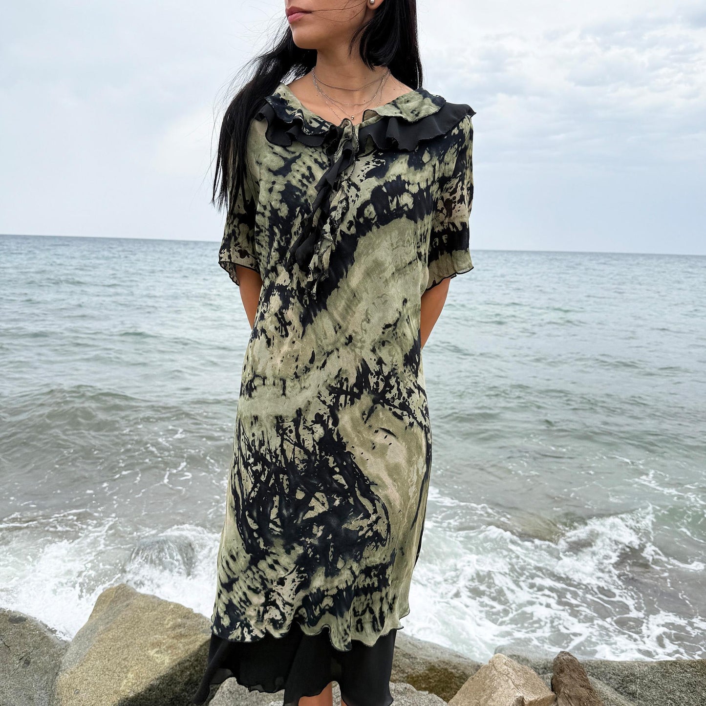 This vintage 90s midi dress features a black and green tie-dye pattern with a ruffled neckline. The short sleeves and flowy layered hem make it ideal for summer festivals, boho gatherings, or dark fairy-inspired looks. A unique Italian-made piece, perfect for forest parties or artistic styling. Made in Italy from lightweight non-stretch fabric. Excellent vintage condition.