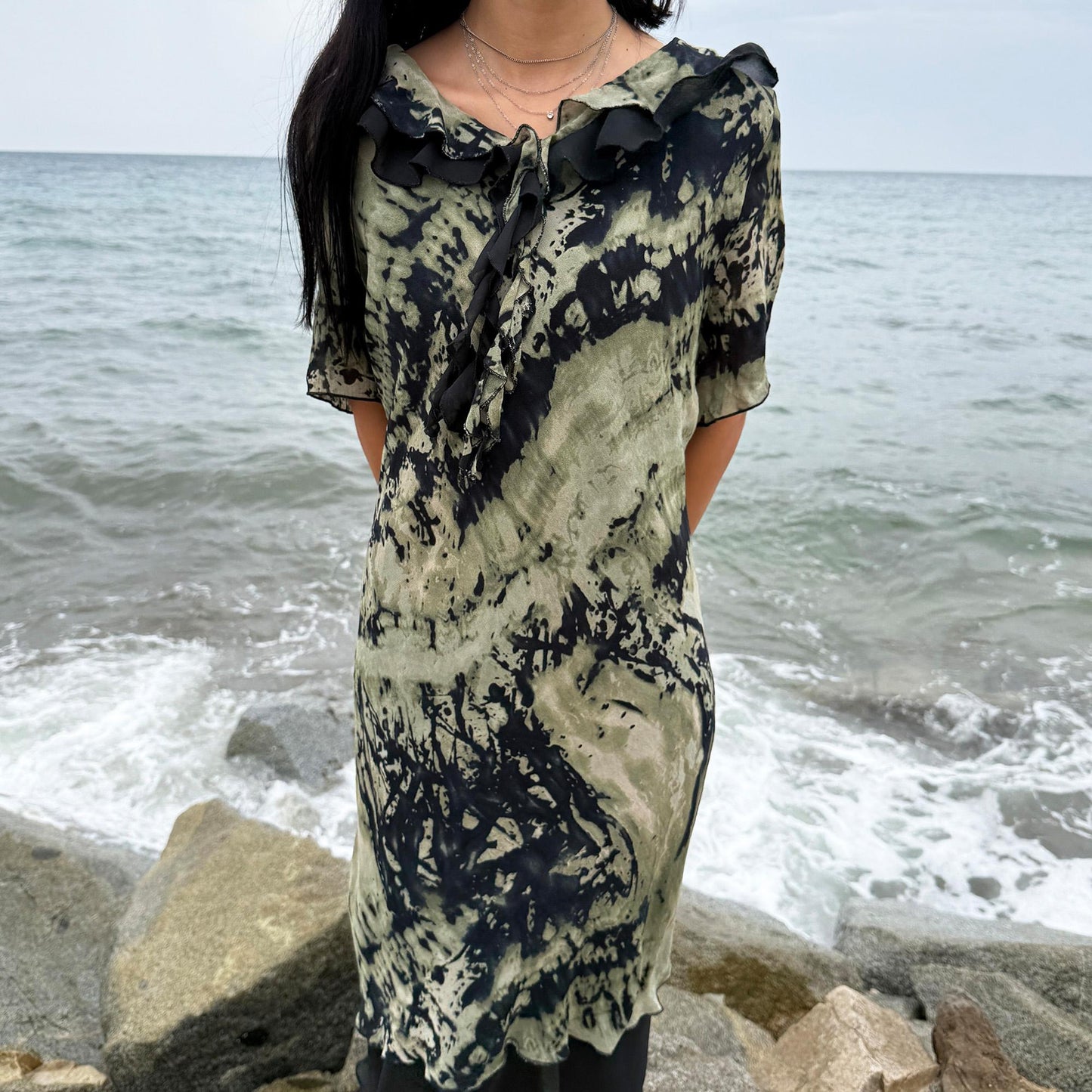 This vintage 90s midi dress features a black and green tie-dye pattern with a ruffled neckline. The short sleeves and flowy layered hem make it ideal for summer festivals, boho gatherings, or dark fairy-inspired looks. A unique Italian-made piece, perfect for forest parties or artistic styling. Made in Italy from lightweight non-stretch fabric. Excellent vintage condition.