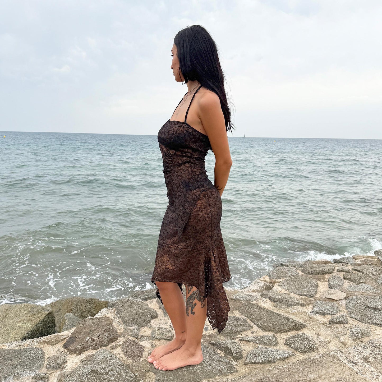 This vintage 2000s two-piece set features a shiny dark bronze-copper and black floral lace pattern. The handkerchief-style asymmetric midi skirt has an elastic waist and is paired with a matching ruched halter tie-neck top with an angled hem. A striking party set, perfect for festivals, summer nights, or dark whimsical styling. A rare archival coord for the ultimate fairy. Made in Spain from a stretchy polyester blend. Excellent vintage condition.