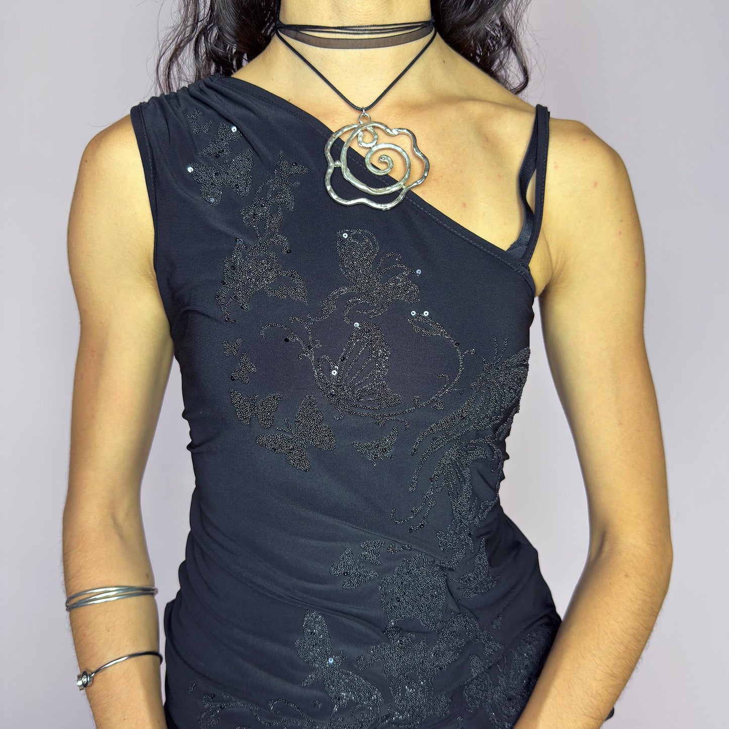 The Y2K Black Sequin Butterfly Top is a vintage 2000s asymmetrical design featuring glittery butterfly motifs, ruched sides, and dual drawstring ties at the shoulder and hem. Crafted from stretchy black fabric with a body-skimming fit, it blends glam detail with subversive edge. Ideal for party nights, clubbing, or iconic festival looks. A millennium-era classic with bold, sculptural energy. Great vintage condition.