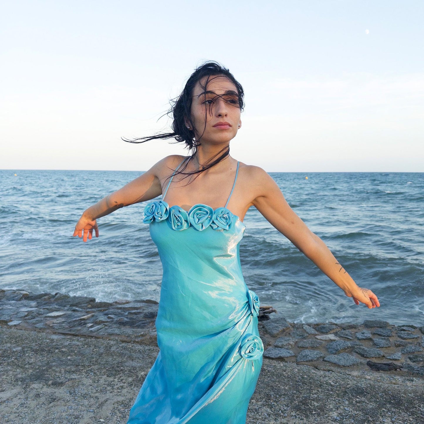 The vintage 2000s blue slip dress is a French-made fantasy with sculptural rosette appliqué along the bust and ruched side detail. Its iridescent finish and fluid midi length evoke a dreamy softness, perfect for proms, summer weddings, or romantic evenings. The silhouette is both delicate and structured, capturing quiet glamour with fairytale allure. A romantic Y2K archive crafted from a shimmering non-stretch fabric. Great vintage condition.