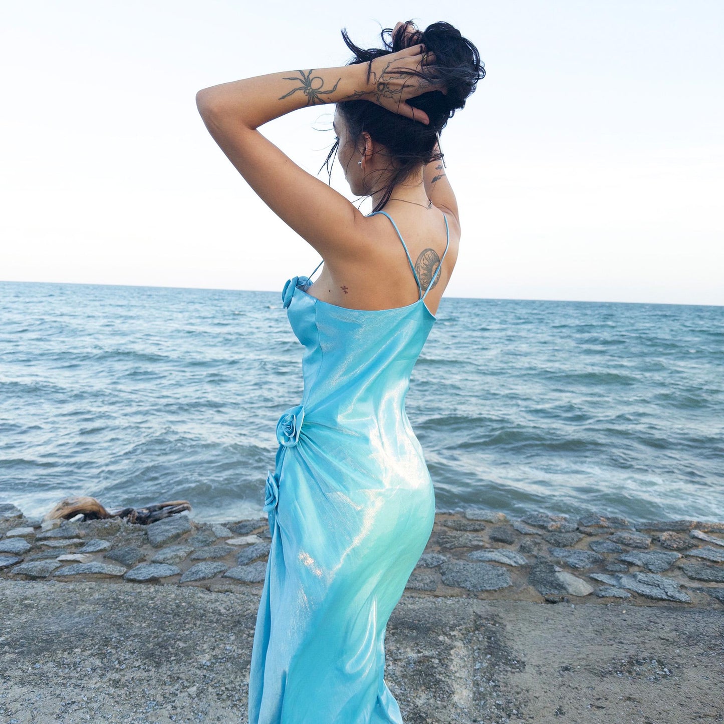 The vintage 2000s blue slip dress is a French-made fantasy with sculptural rosette appliqué along the bust and ruched side detail. Its iridescent finish and fluid midi length evoke a dreamy softness, perfect for proms, summer weddings, or romantic evenings. The silhouette is both delicate and structured, capturing quiet glamour with fairytale allure. A romantic Y2K archive crafted from a shimmering non-stretch fabric. Great vintage condition.