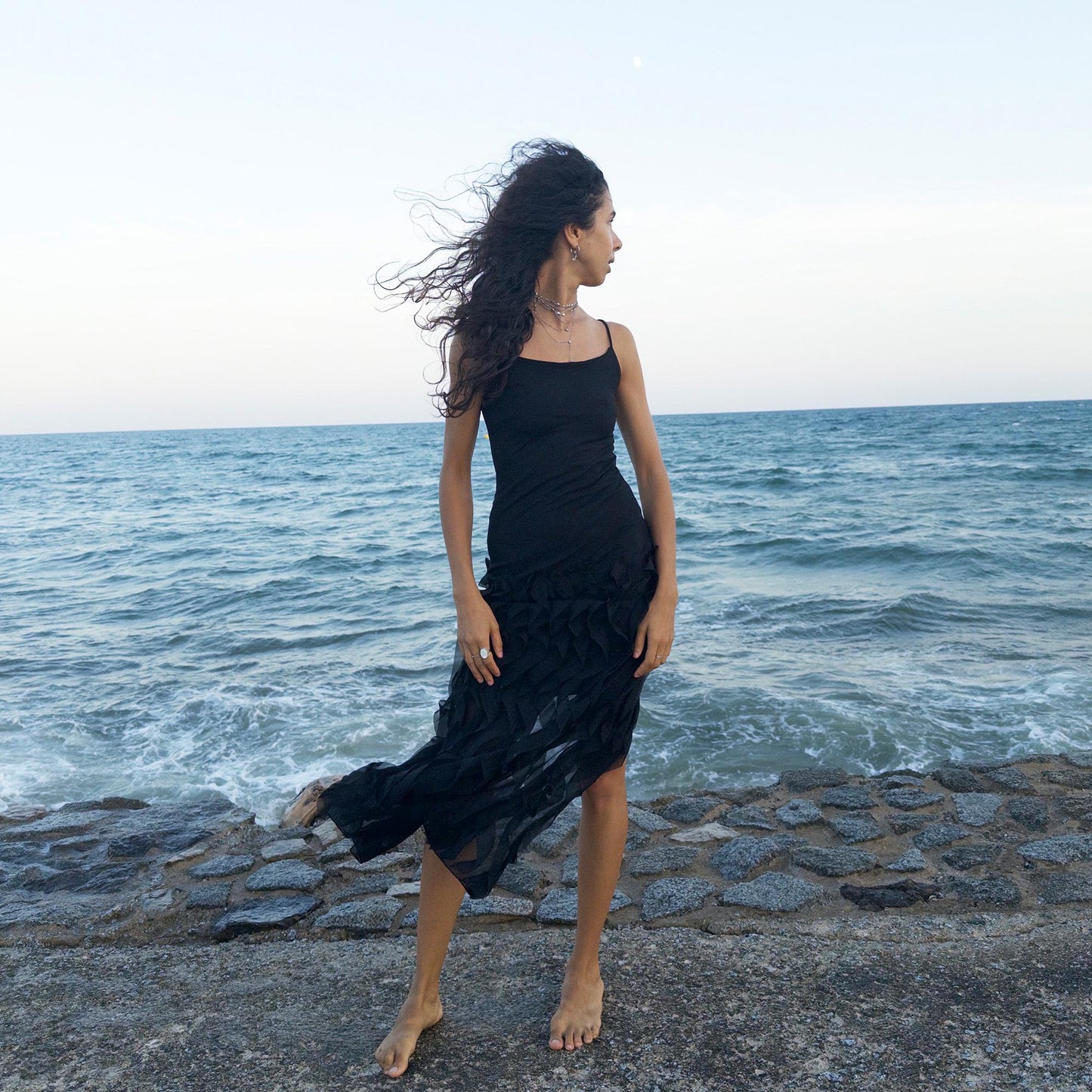 The vintage 90s black mesh midi dress is a sculptural piece with sheer wave appliqué layered across the skirt, minimalist neckline, and a back slit for fluidity. Its body-skimming silhouette fuses quiet sensuality with architectural edge. Ideal for city nights, gallery parties, or modern cocktail looks. An avant garde archive find made in the USA from a stretchy polyester blend. Excellent vintage condition.