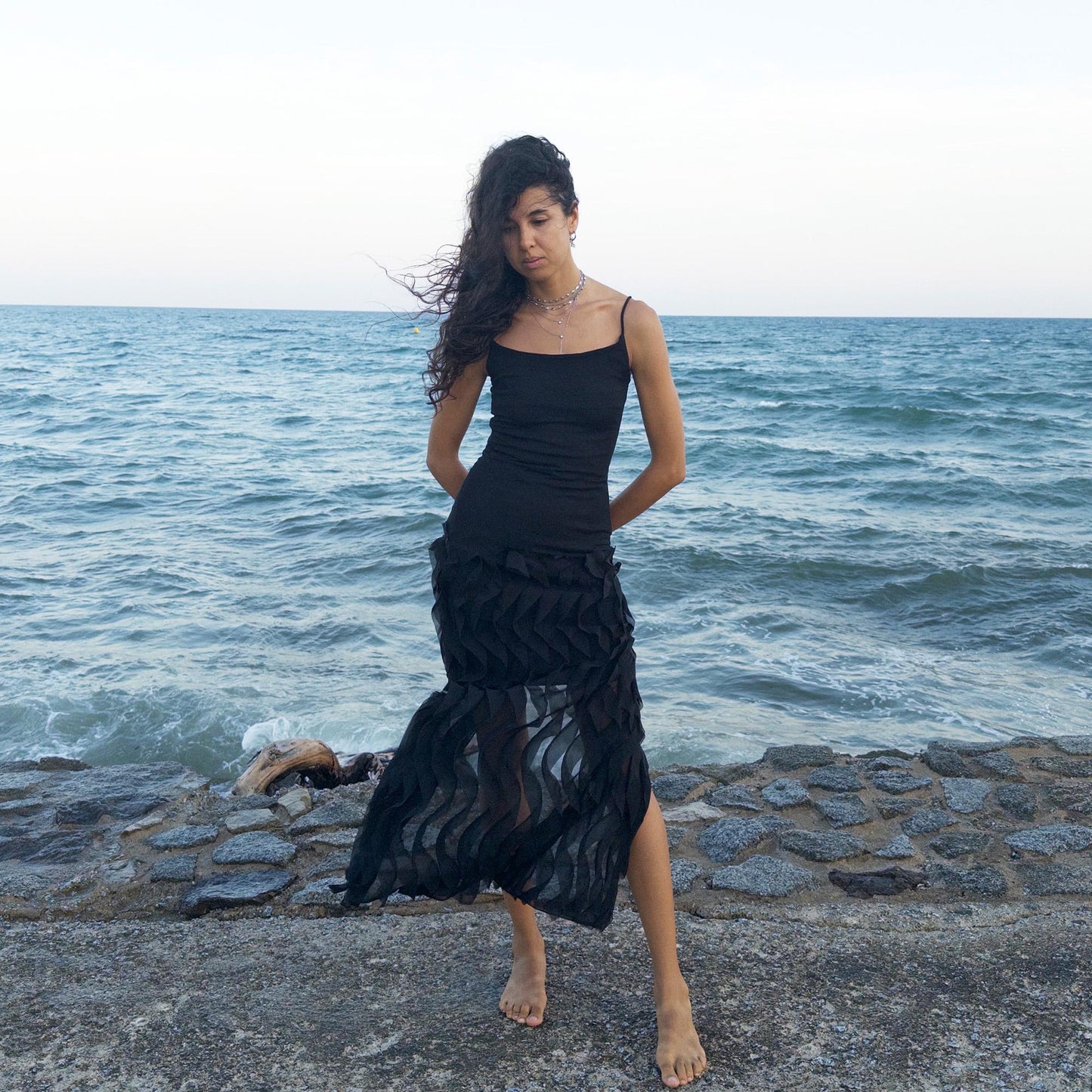 The vintage 90s black mesh midi dress is a sculptural piece with sheer wave appliqué layered across the skirt, minimalist neckline, and a back slit for fluidity. Its body-skimming silhouette fuses quiet sensuality with architectural edge. Ideal for city nights, gallery parties, or modern cocktail looks. An avant garde archive find made in the USA from a stretchy polyester blend. Excellent vintage condition.
