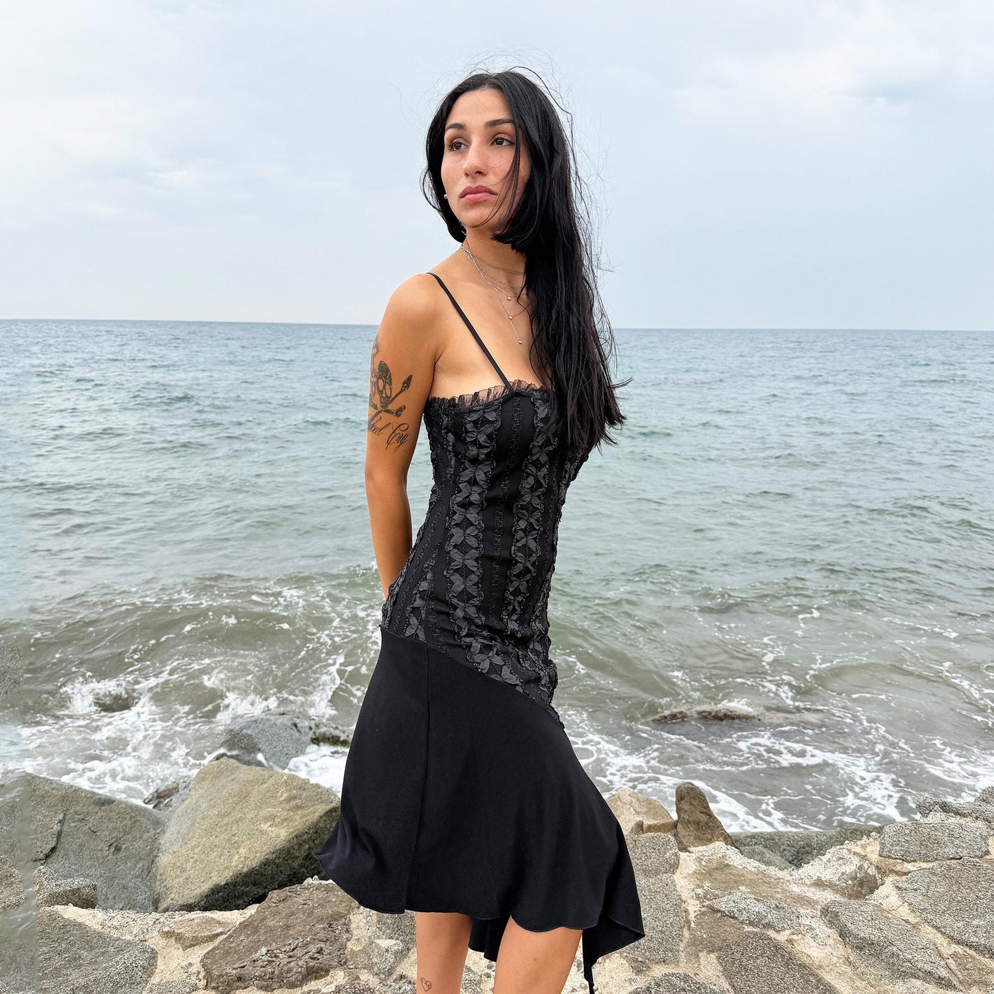This vintage 2000s black midi dress features an asymmetrical handkerchief hem with whimsical flow and delicate mesh panel details through the bodice. Crafted in France from a stretchy polyester blend, it hugs the figure while allowing movement. A romantic dark piece with fairy, witchy, and night-party energy—perfect for Y2K alternative styling. Made from polyester stretch blend. Excellent vintage condition.