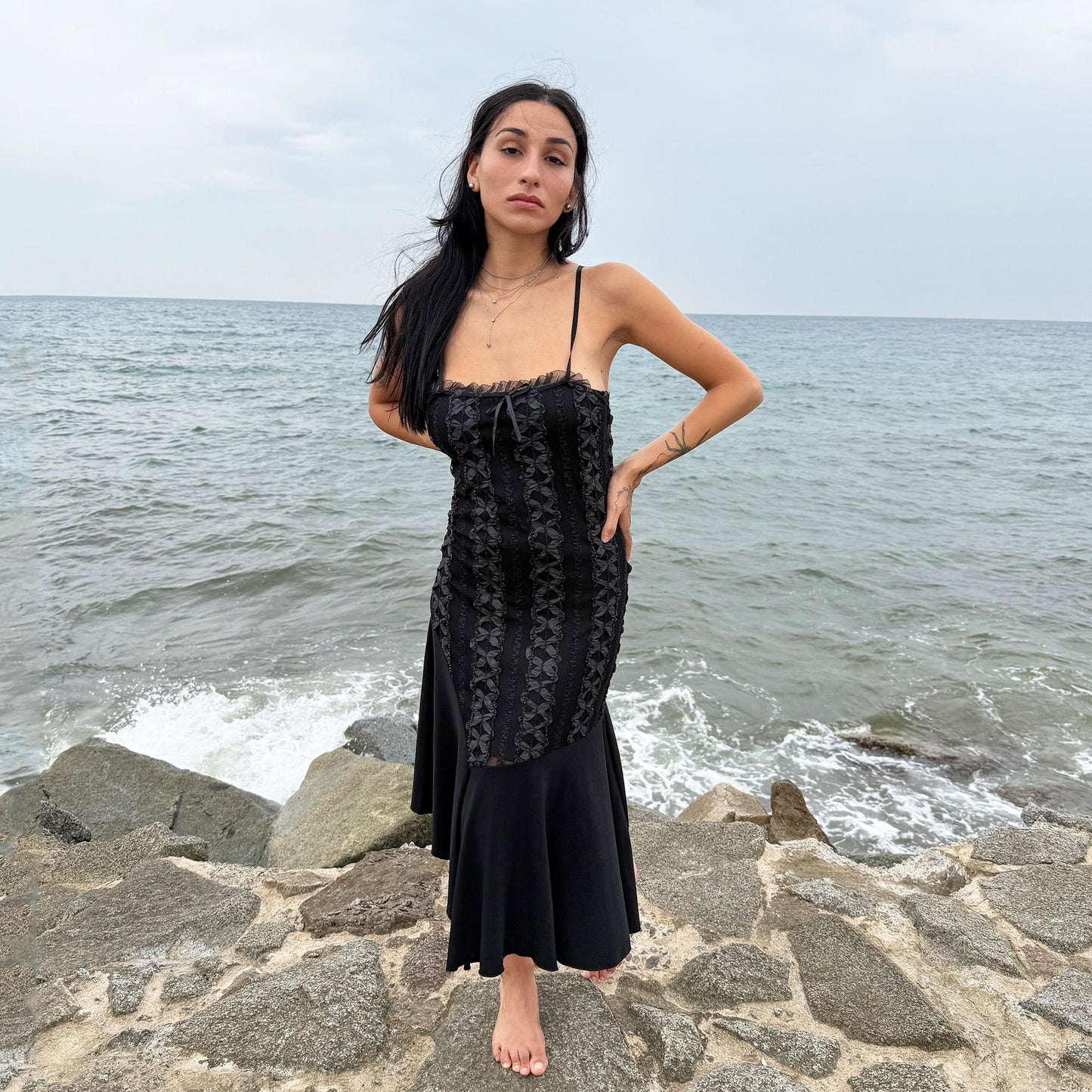 This vintage 2000s black midi dress features an asymmetrical handkerchief hem with whimsical flow and delicate mesh panel details through the bodice. Crafted in France from a stretchy polyester blend, it hugs the figure while allowing movement. A romantic dark piece with fairy, witchy, and night-party energy—perfect for Y2K alternative styling. Made from polyester stretch blend. Excellent vintage condition.
