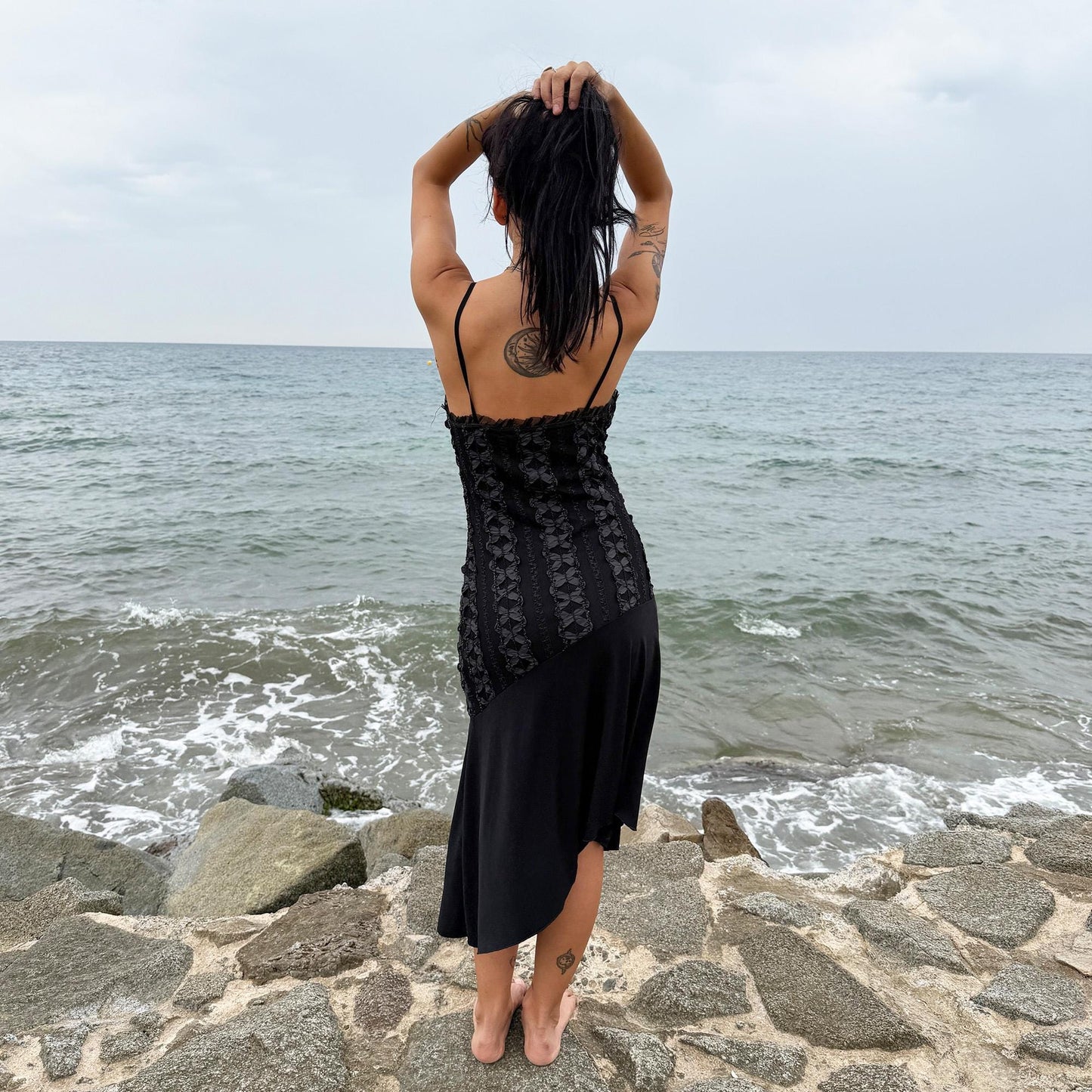 This vintage 2000s black midi dress features an asymmetrical handkerchief hem with whimsical flow and delicate mesh panel details through the bodice. Crafted in France from a stretchy polyester blend, it hugs the figure while allowing movement. A romantic dark piece with fairy, witchy, and night-party energy—perfect for Y2K alternative styling. Made from polyester stretch blend. Excellent vintage condition.