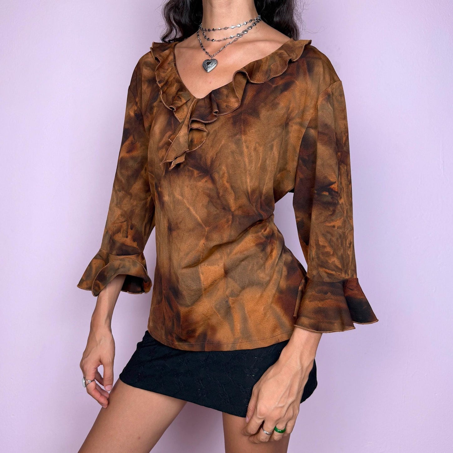 This vintage 2000s brown tie-dye top features a ruffle neckline and three-quarter bell sleeves. Made from stretchy fabric, it channels fairycore with earthy depth and whimsical structure. A perfect piece for boho layering, festival nights, or forest-inspired edits. Made in Spain from a polyester blend. Excellent vintage condition.