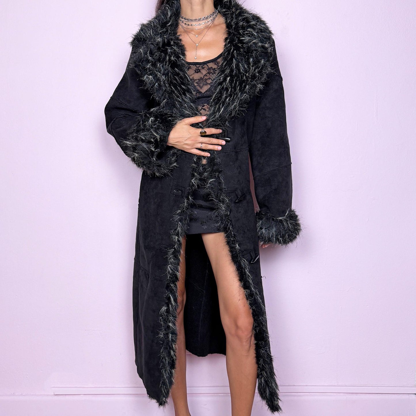 This vintage 2000s black maxi Penny Lane coat features a plush faux suede shell with dramatic black-and-beige faux fur trim at the collar and cuffs. Designed with toggle closures and side pockets, it offers warmth and structure while exuding bohemian gothic elegance. The long silhouette and textured fur detailing create a striking statement—perfect for winter nights, city wear, or whimsical Y2K layering. Made from polyester acrylic blend. Excellent vintage condition.