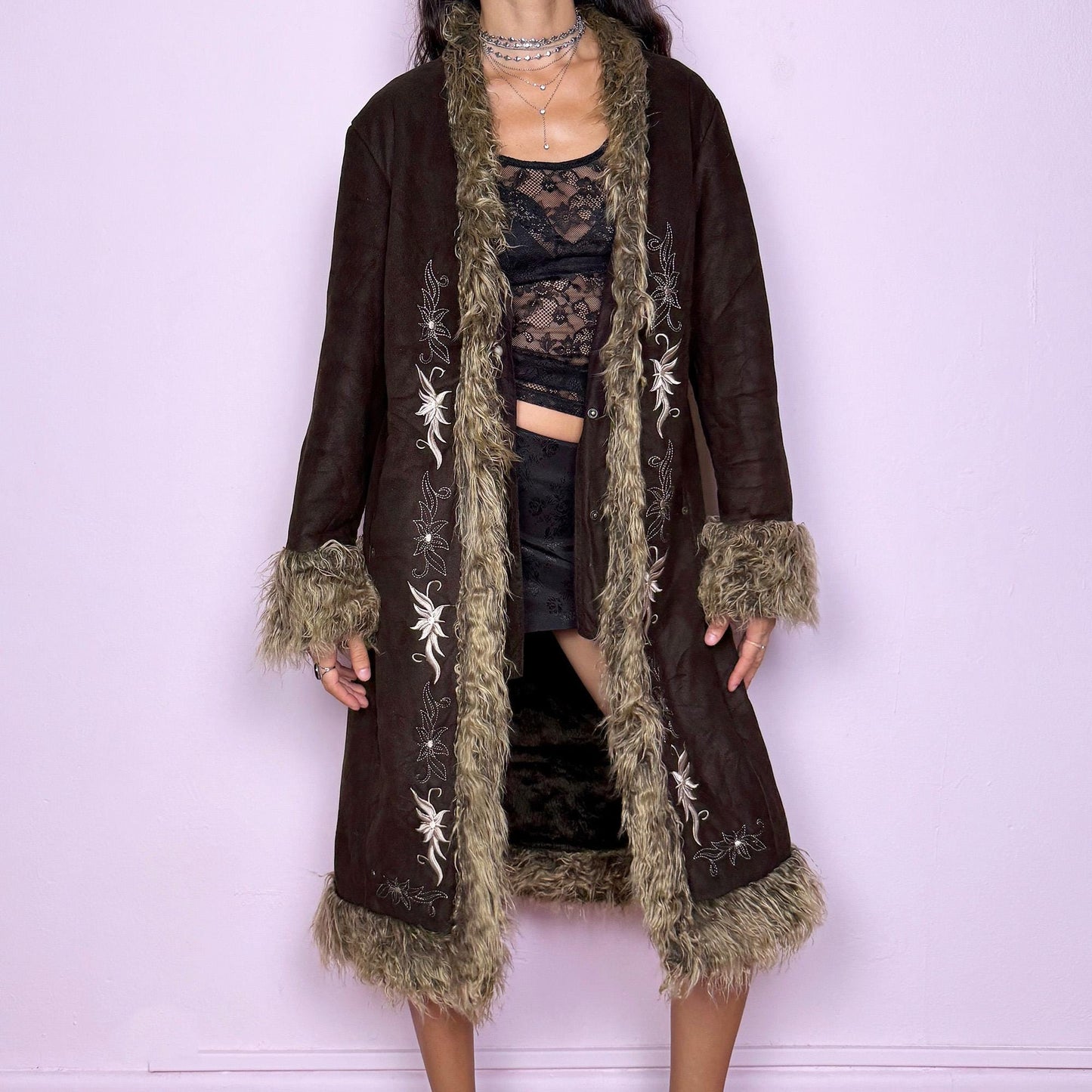 This vintage 2000s dark brown Penny Lane coat features beige faux fur trim at the collar, cuffs, and hem, with intricate floral embroidery along the front. Crafted from soft faux suede with pockets and dual snap-and-hook closure, it embodies the whimsical 70s Afghan-inspired Y2K aesthetic. Warm and romantic—perfect for fairycore, boho, and forest muse styling. Made from polyester faux suede and faux fur. Great vintage condition.