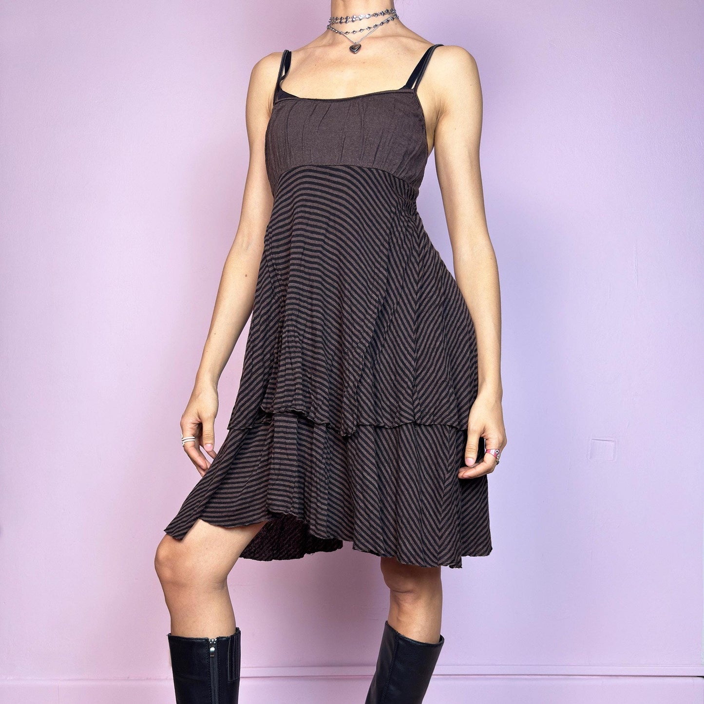 This vintage 2000s brown midi dress features a fine black stripe pattern, square neckline, and thin shoulder straps. Made from a soft, stretchy knit, it has an empire waist and a tiered asymmetric hem that drapes with ease. Perfect for summer. A casual, fairy grunge–inspired piece with subtle volume and flow—blending comfort, minimalism, and quiet edge. Great vintage condition.