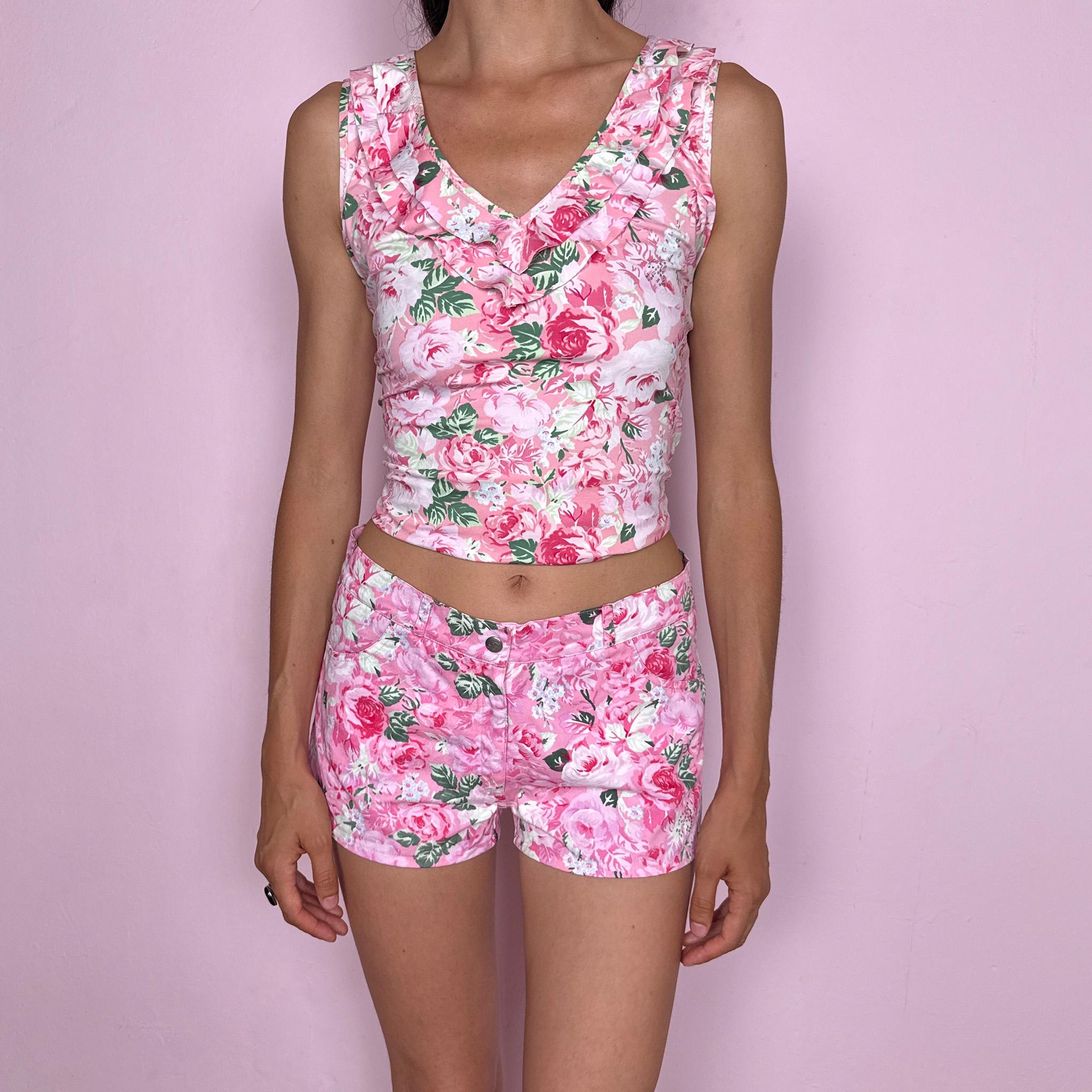 Vintage 2000s Blumarine Beachwear shorts, made in Italy from 100% cotton with a structured no-stretch feel and a mid-rise fit. Designed in a pink romantic floral print with roses and green leaf details, they feature a front button and zip closure, pockets, and a rhinestone Blumarine logo detail for a Y2K finish. A rare and feminine Italian designer piece, ideal for a girly summer look. Excellent vintage condition.