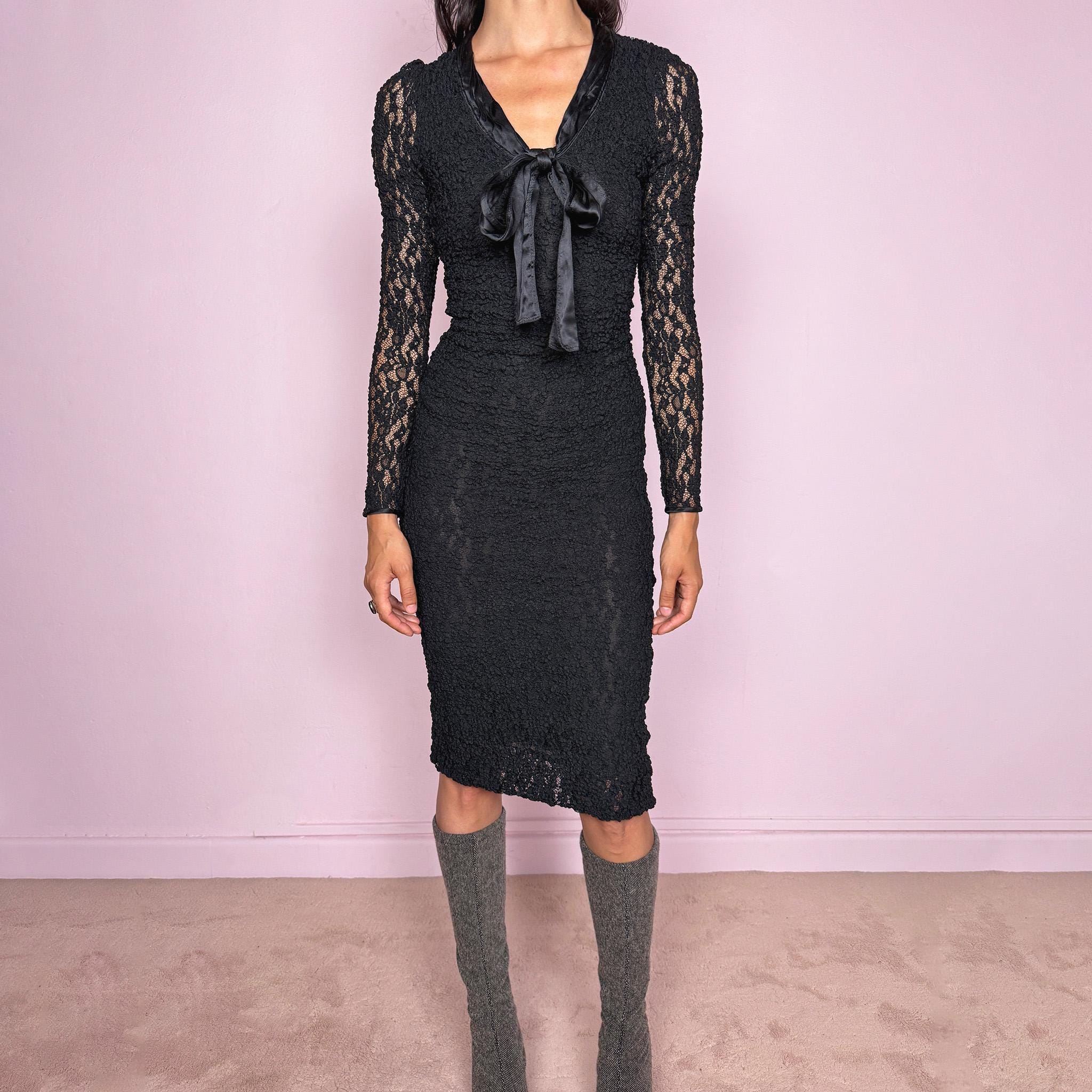 Vintage 2000s D&G Dolce & Gabbana black long sleeve midi dress crafted from stretchy silk-blend textured lace fabric. Fitted silhouette with sheer long sleeves, side zip closure, and satin bow tie detail at the neckline. A dark romantic designer piece with a sharp feminine silhouette, perfect for evening wear. Main fabric is polyamide and silk blend; lining is 93% silk and 7% elastane. Excellent vintage condition.